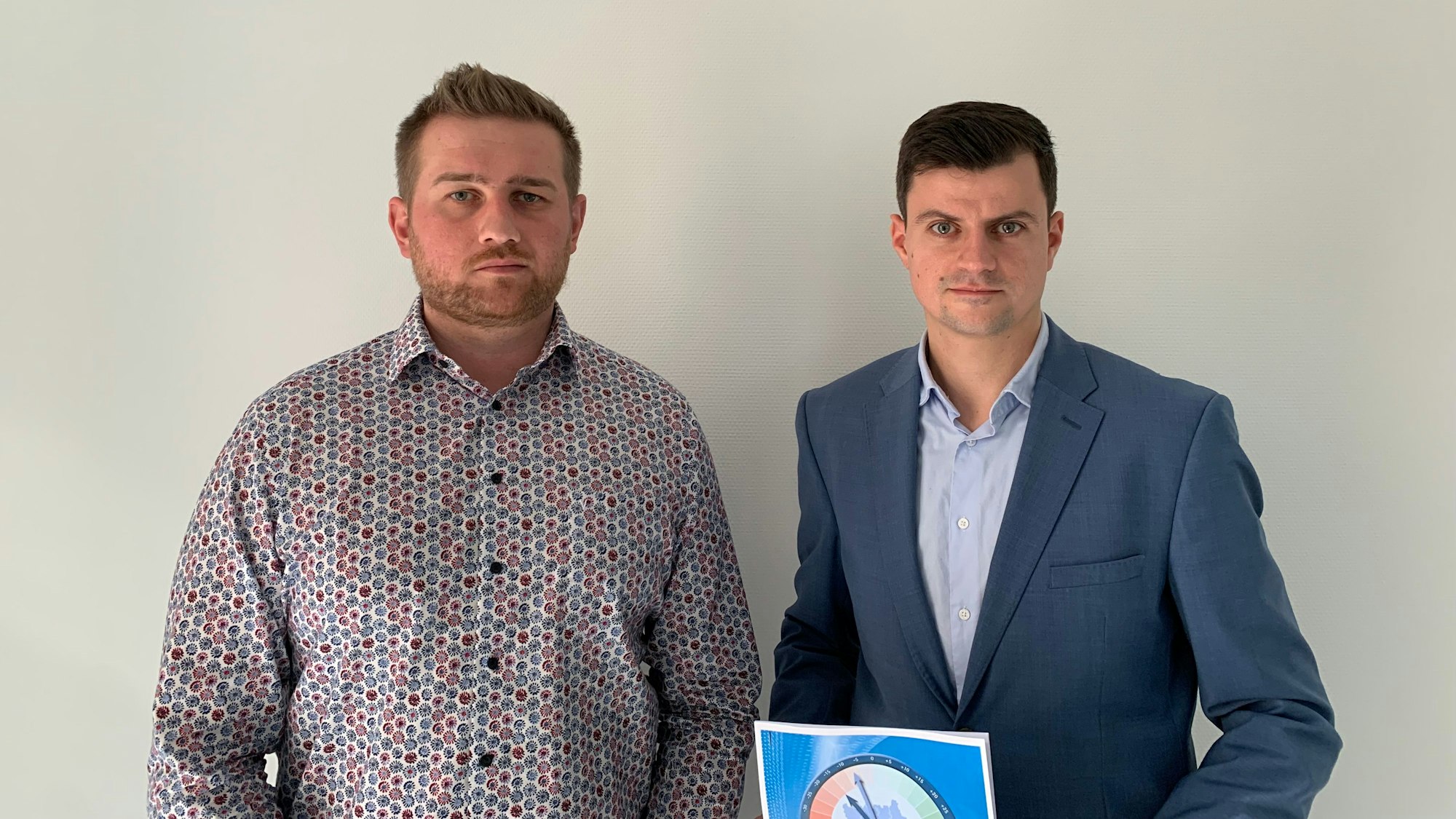 Zwei Männer stehen vor einer Wand.