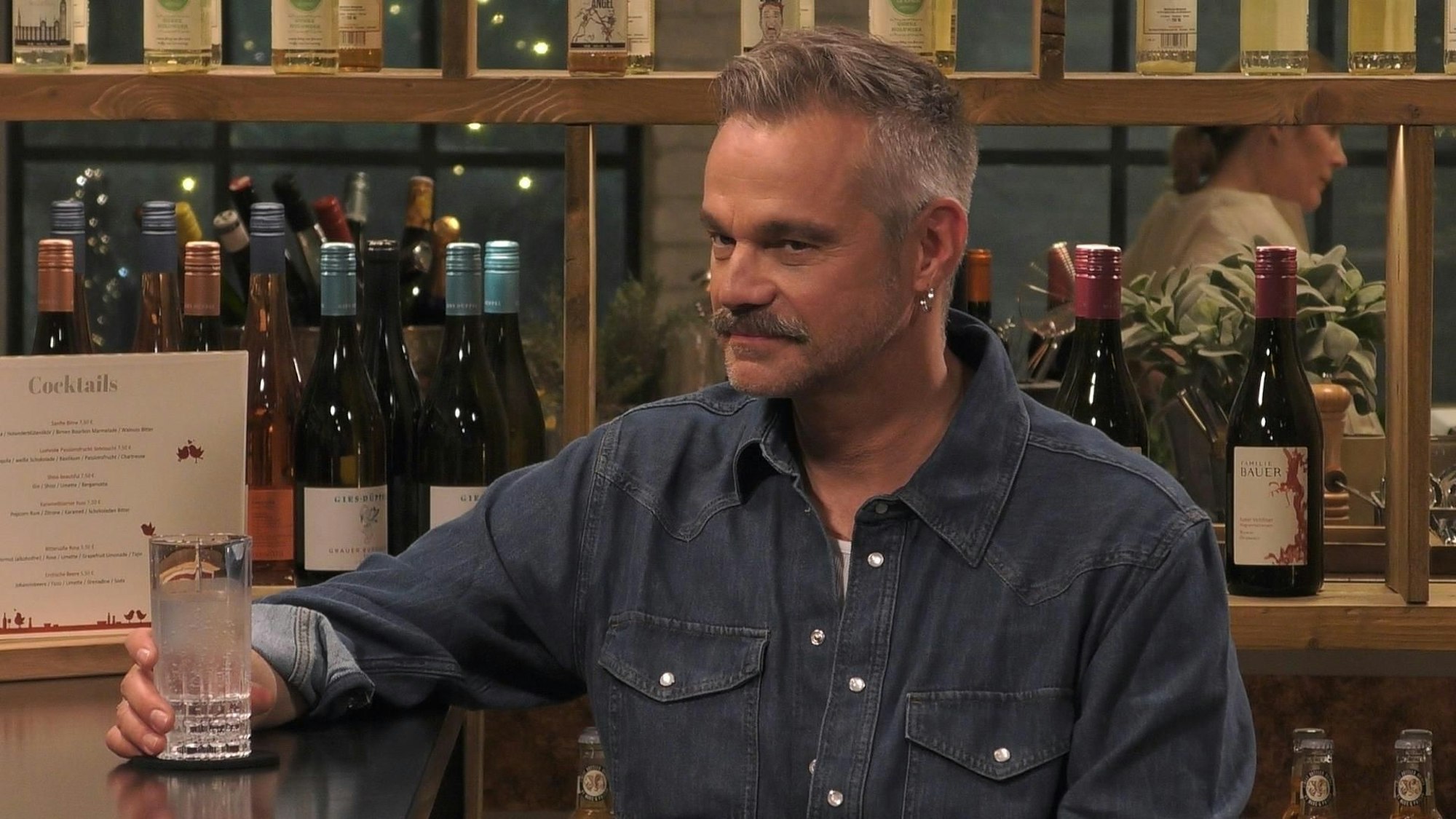 Raphael kann sich sein Date aus sicherer Entfernung schon einmal anschauen, bevor es zu Tisch geht. Er sitzt am Tresen einer Bar.