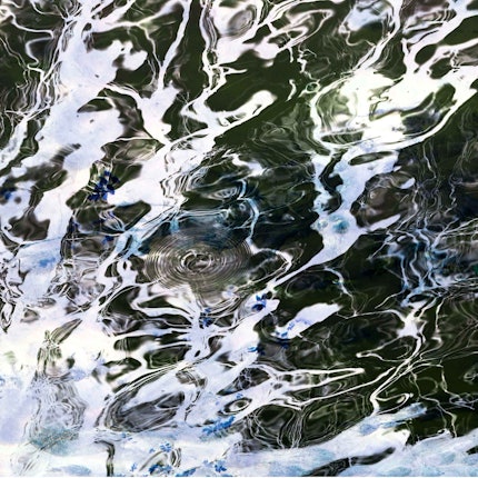 Das Bild zeigt eine abstrakte Spiegelung auf einer Wasserfläche.