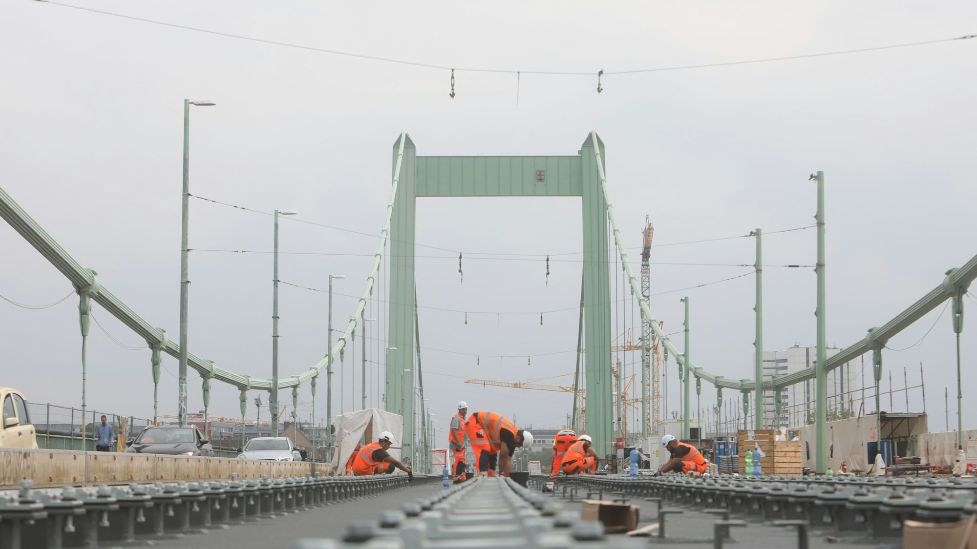 Bauarbeiter arbeiten auf den Gleisen der Mülheimer Brücke.