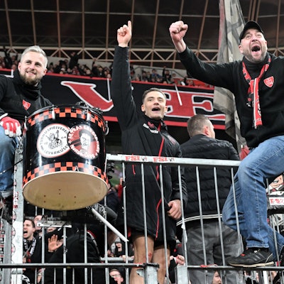 Florian Wirtz (M.) feiert mit den Leverkusener Ultras auf dem Zaun.