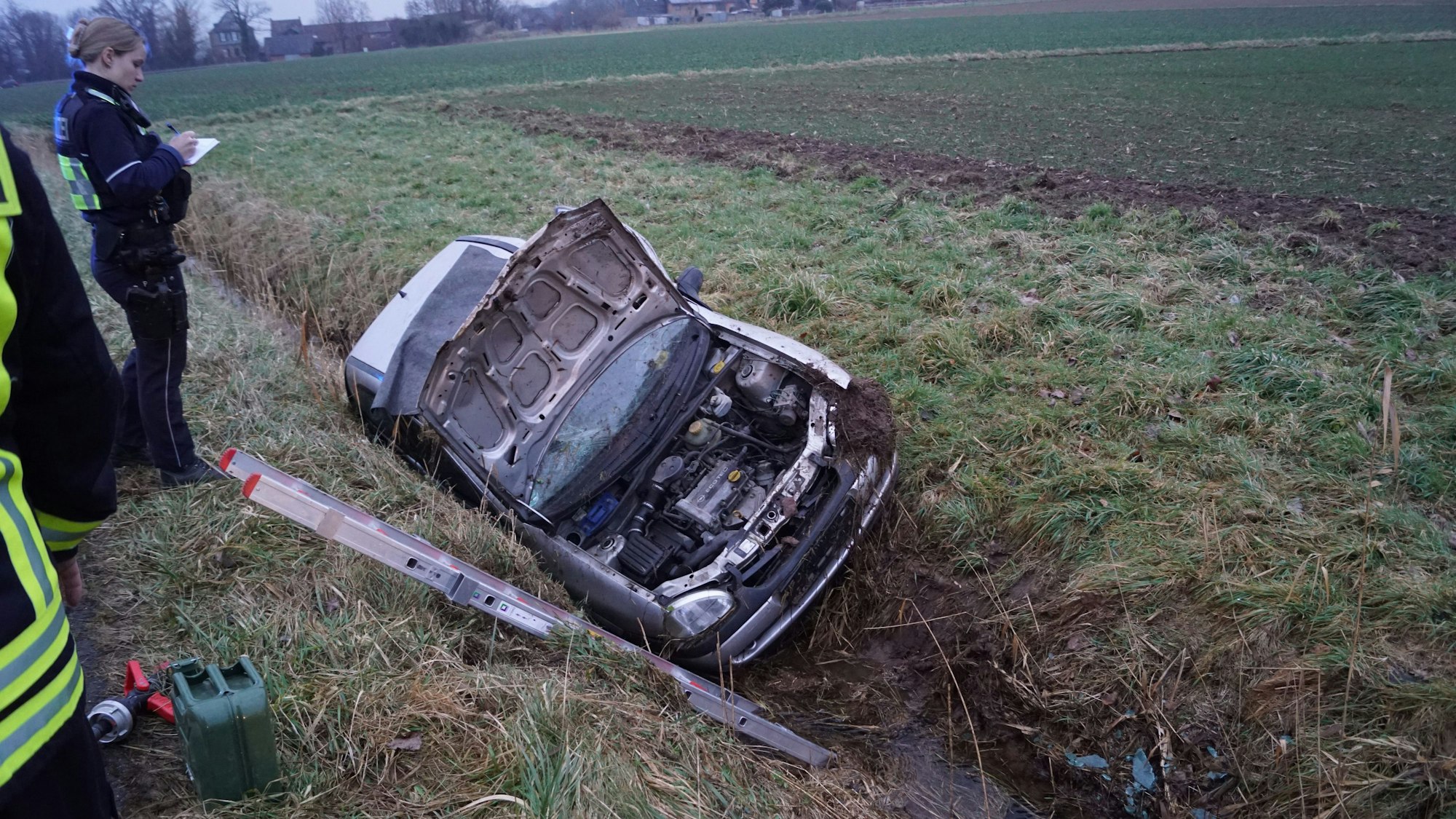 Das Bild zeigt den Kleinwagen, der im Straßengraben liegt. Die Motorhaube ist geöffnet.