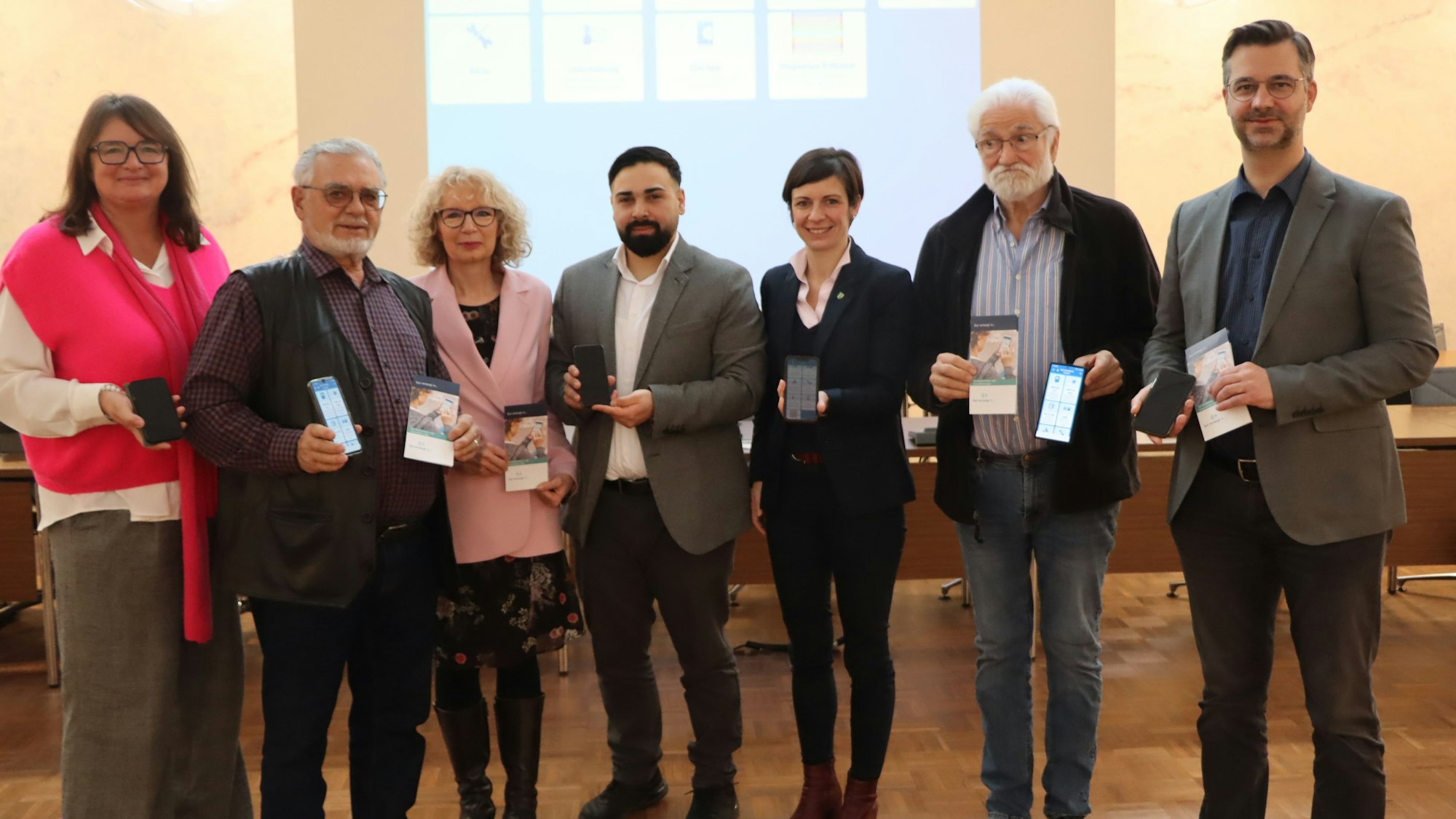 Männer und Frauen stehen vor einer Leinwand.