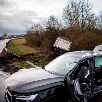 Das Bild zeigt ein stark beschädigtes Auto. Im Hintergrund liegt ein Sattelschlepper im Graben.
