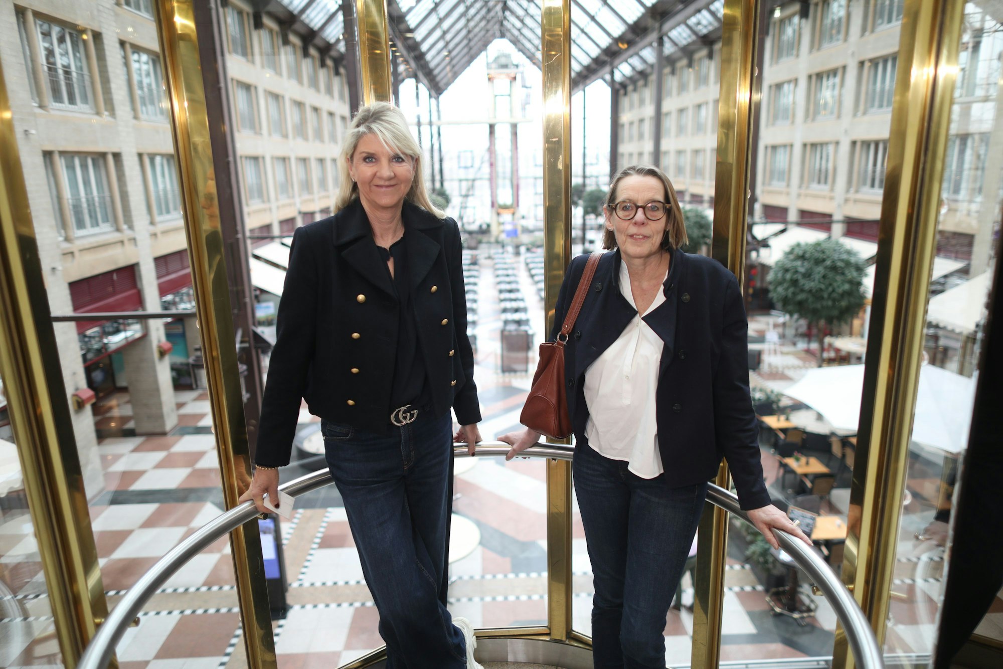 Christiane Blaeser von der Agentur „Connected“ und Anne Rossenbach vom SkF stehen im gläsernen Aufzugs des Kölner Maritim-Hotels.