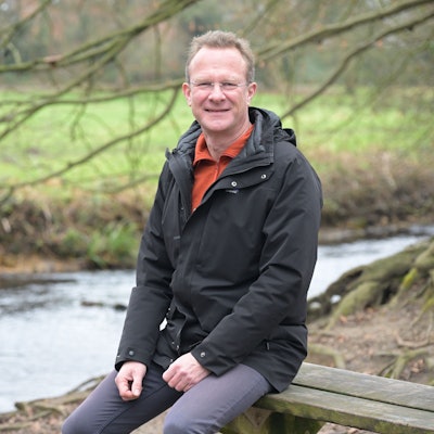Maik Außendorf sitzt auf einer Bank am Mutzbach.