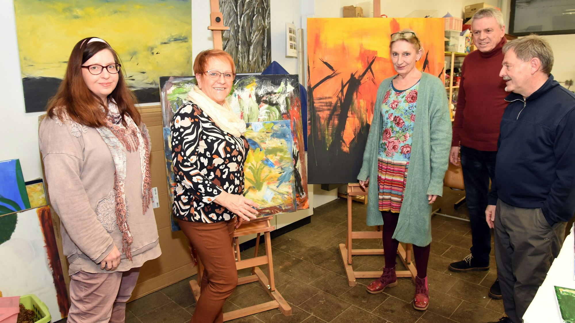 Das Foto zeigt Dozenten und Organisatoren des Kunstbahnhofs vor bunten Bildern.