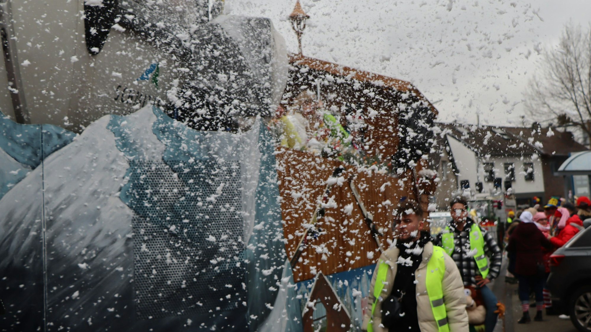 Das Bild zeigt Wagenengel neben einem Karnevalswagen.