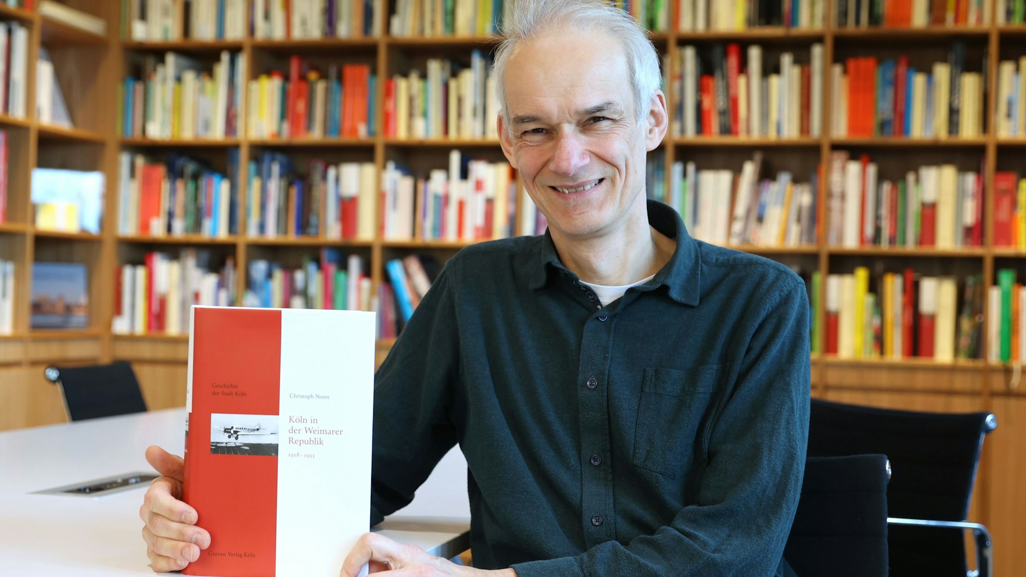 Christoph Nonn lächelt in die Kamera und hält sein Buch in der Hand.