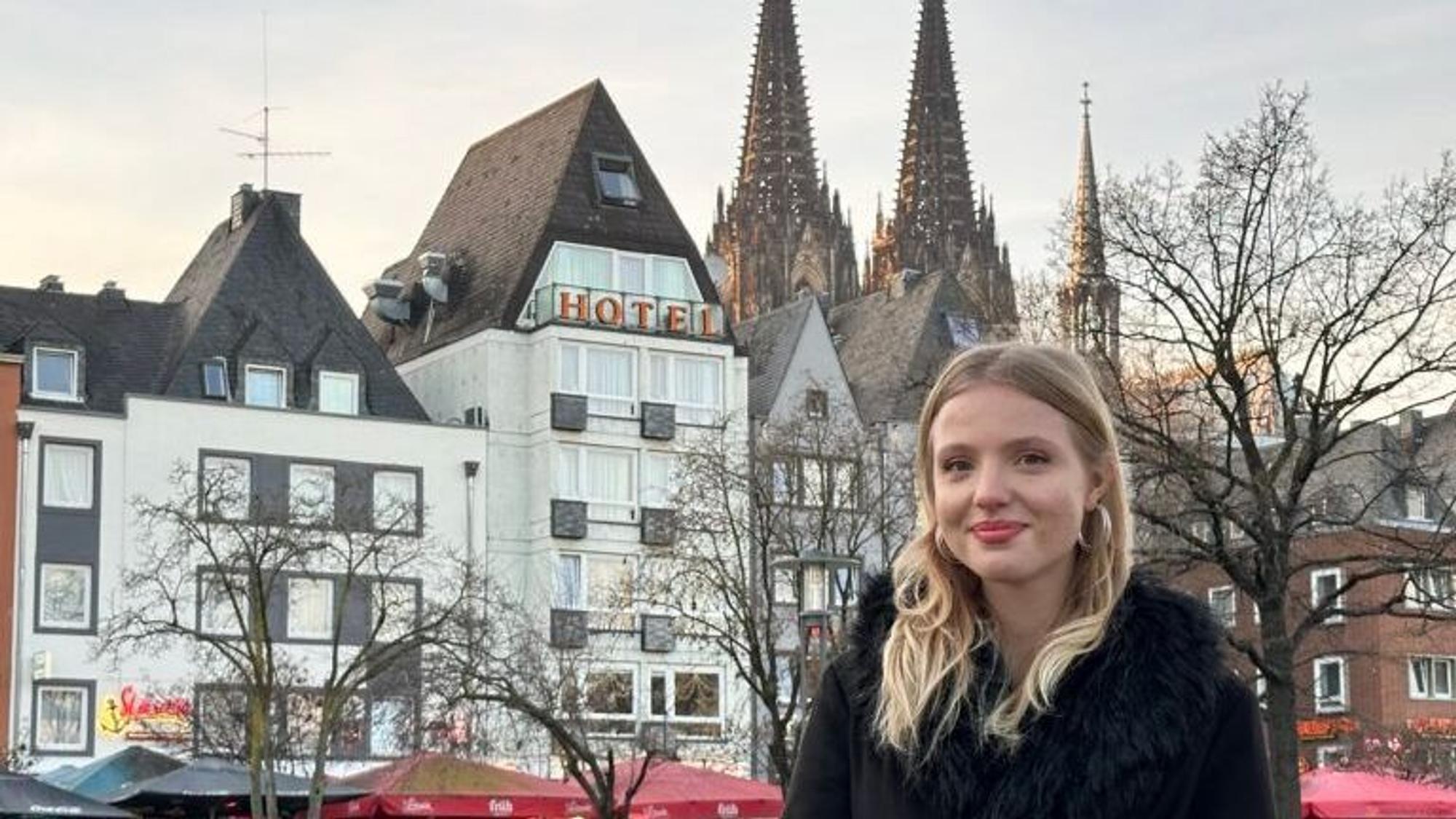Kateryna Knaub ist Vorstandsmitglied der Bezirksschüler*innenvertretung und steht auf dem Foto in der Kölner Altstadt mit dem Dom im Hintergrund.