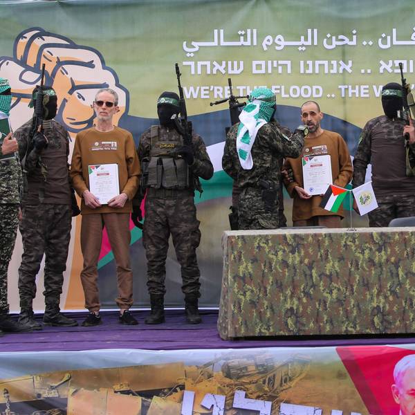 Palestinian Hamas fighters escort(L-R) Ohad Ben Ami, Or Levy and Eli Sharabi on a stage before handing them over to a Red Cross team in Deir el-Balah, central Gaza, on February 8, 2025, as part of the fifth hostage-prisoner exchange of a fragile ceasefire. The swap comes after US President Donald Trump proposed clearing out the Gaza Strip of its inhabitants and for the United States to take over the Palestinian territory -- a plan that has sparked global uproar and been rejected by Hamas. (Photo by Eyad BABA / AFP)