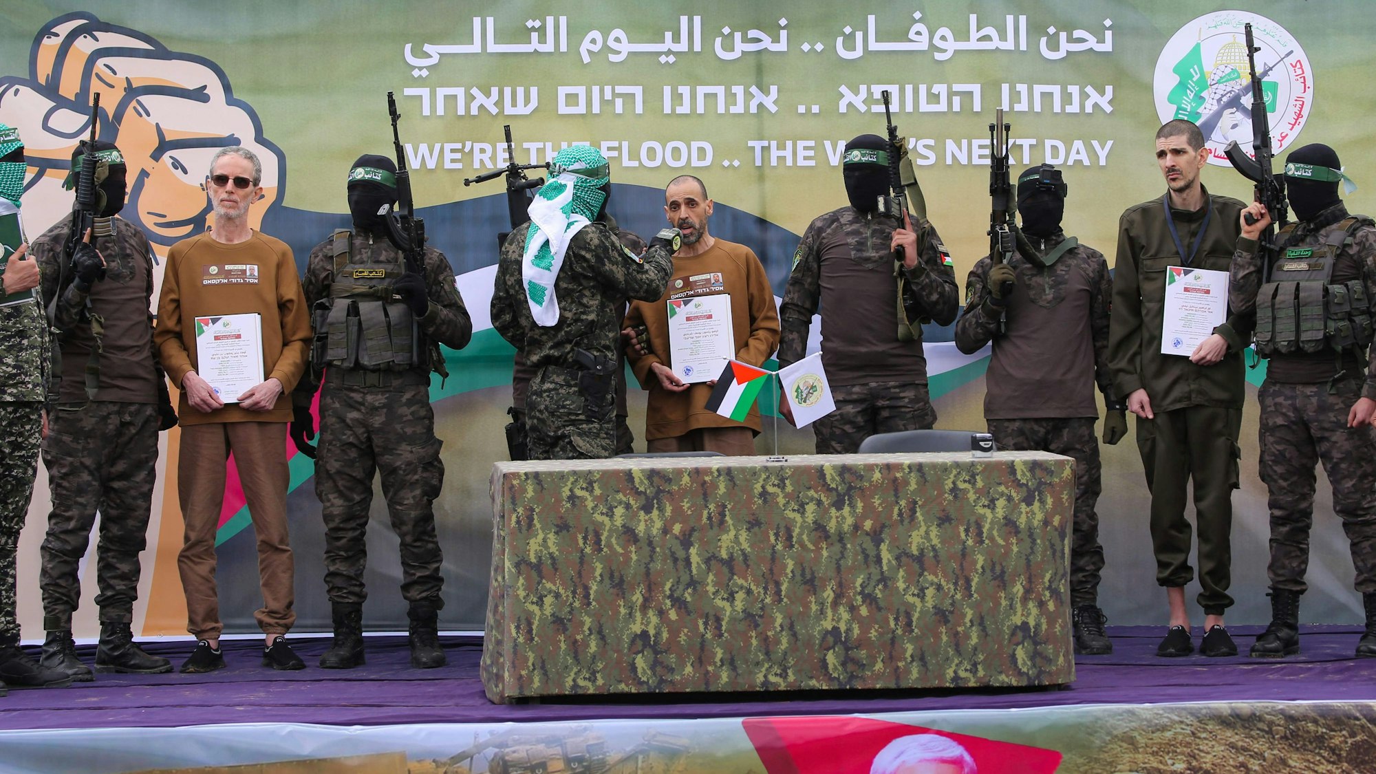 Palestinian Hamas fighters escort(L-R) Ohad Ben Ami, Or Levy and Eli Sharabi on a stage before handing them over to a Red Cross team in Deir el-Balah, central Gaza, on February 8, 2025, as part of the fifth hostage-prisoner exchange of a fragile ceasefire. The swap comes after US President Donald Trump proposed clearing out the Gaza Strip of its inhabitants and for the United States to take over the Palestinian territory -- a plan that has sparked global uproar and been rejected by Hamas. (Photo by Eyad BABA / AFP)
