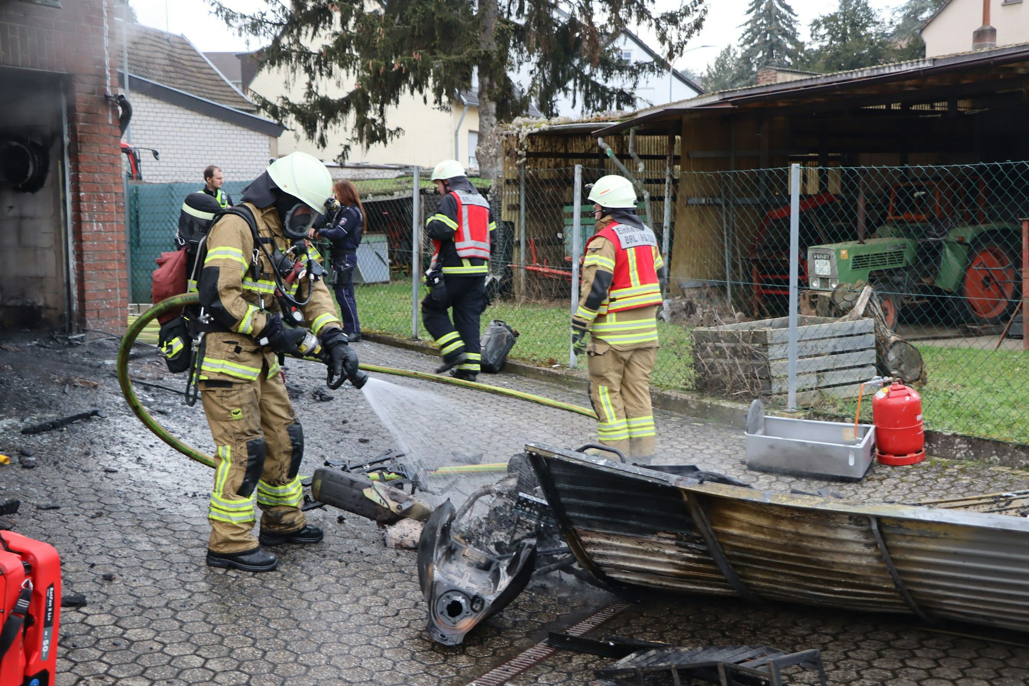 Nachlöscharbeiten im Hof vor der Garage. Das Motorrad ist bis zur Unkenntlichkeit verbrannt.