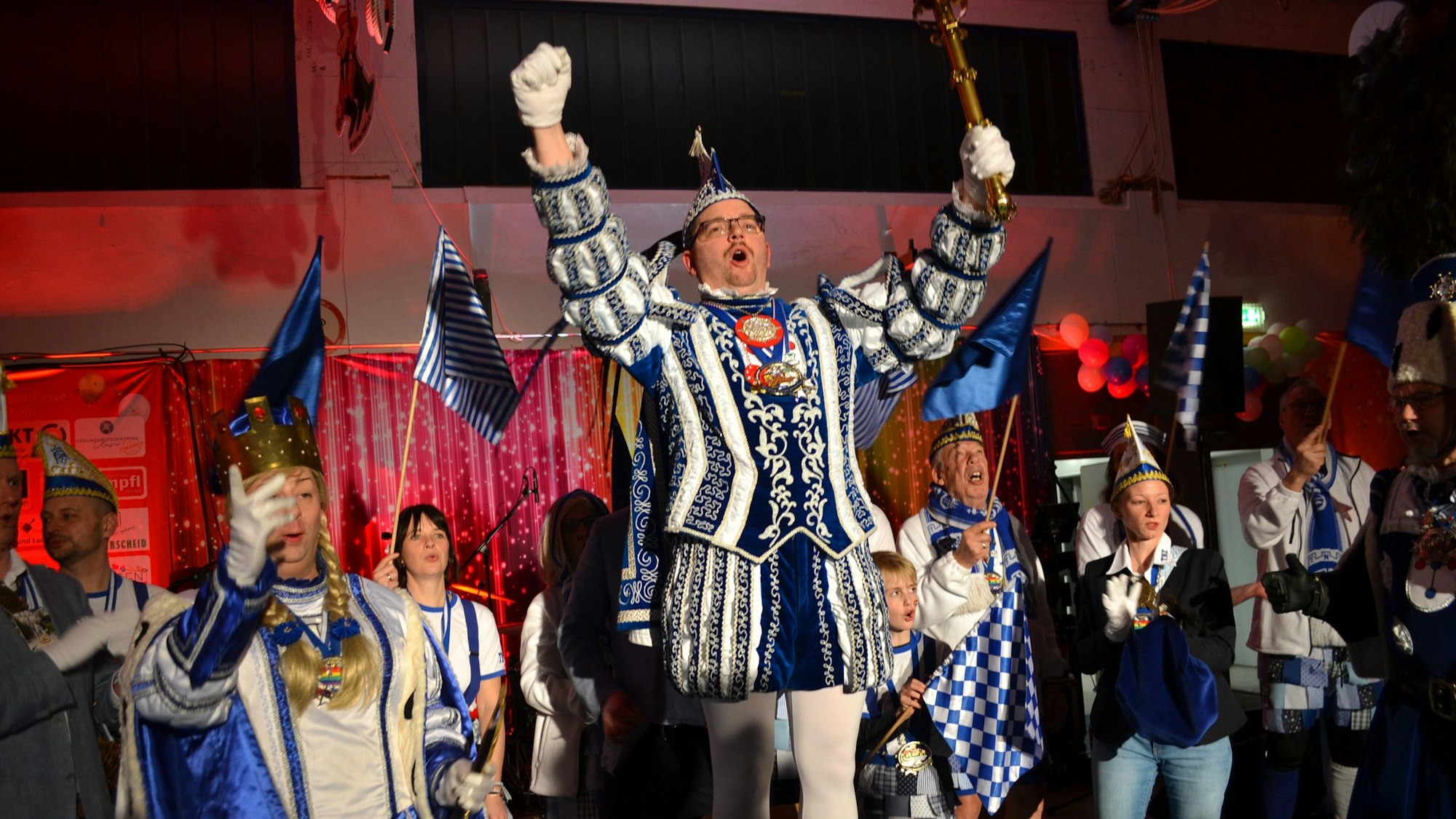 Menschen in Karnevalsoutfits jubeln auf einer Bühne.