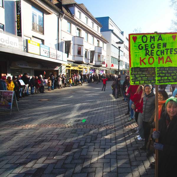 Das Foto zeigt eine Menschenkette, eine der Teilnehmerinnen hält ein Schild mit der Aufschrift "Oma gegen rechtes Koma".