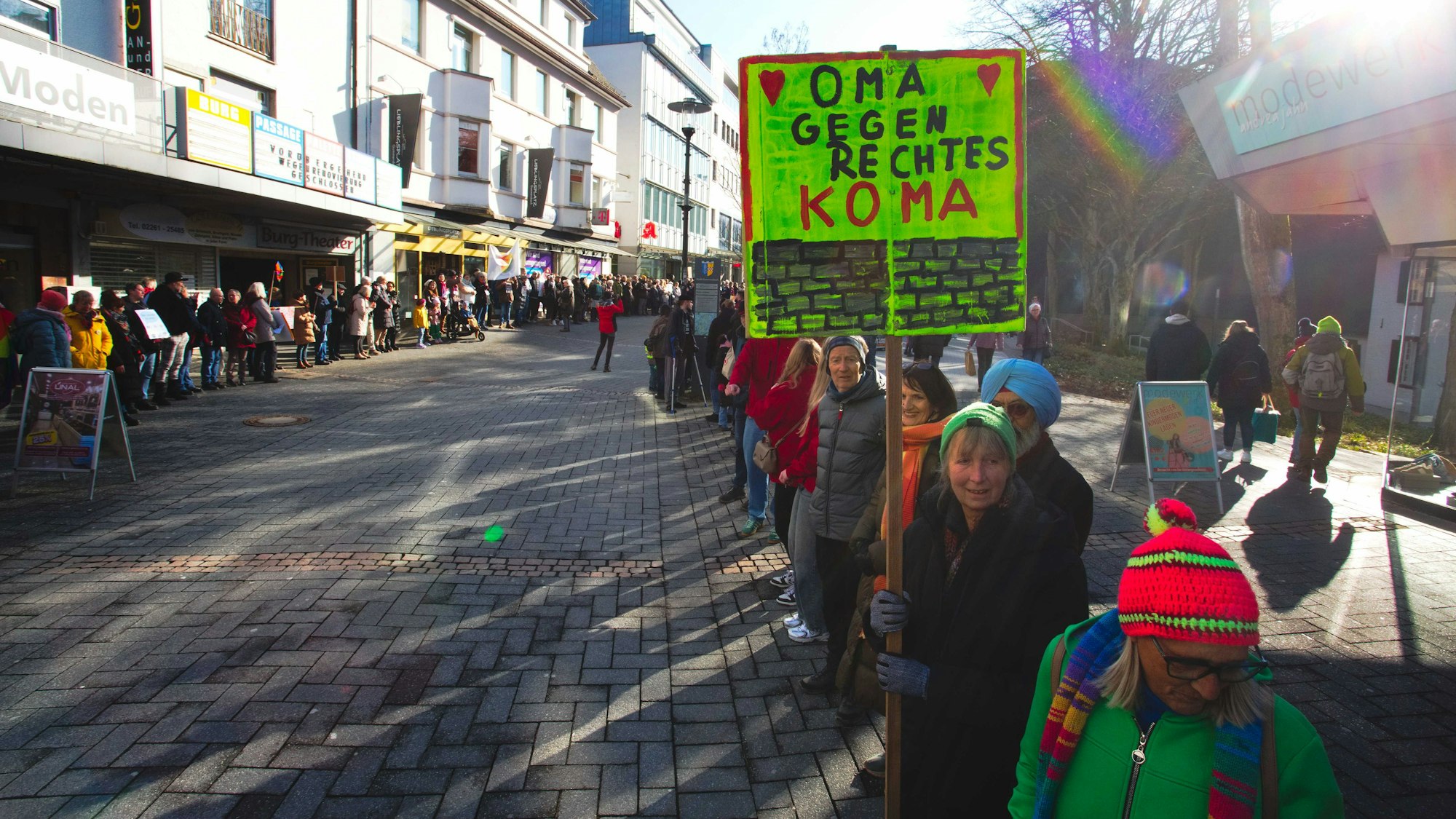 Das Foto zeigt eine Menschenkette, eine der Teilnehmerinnen hält ein Schild mit der Aufschrift "Oma gegen rechtes Koma".