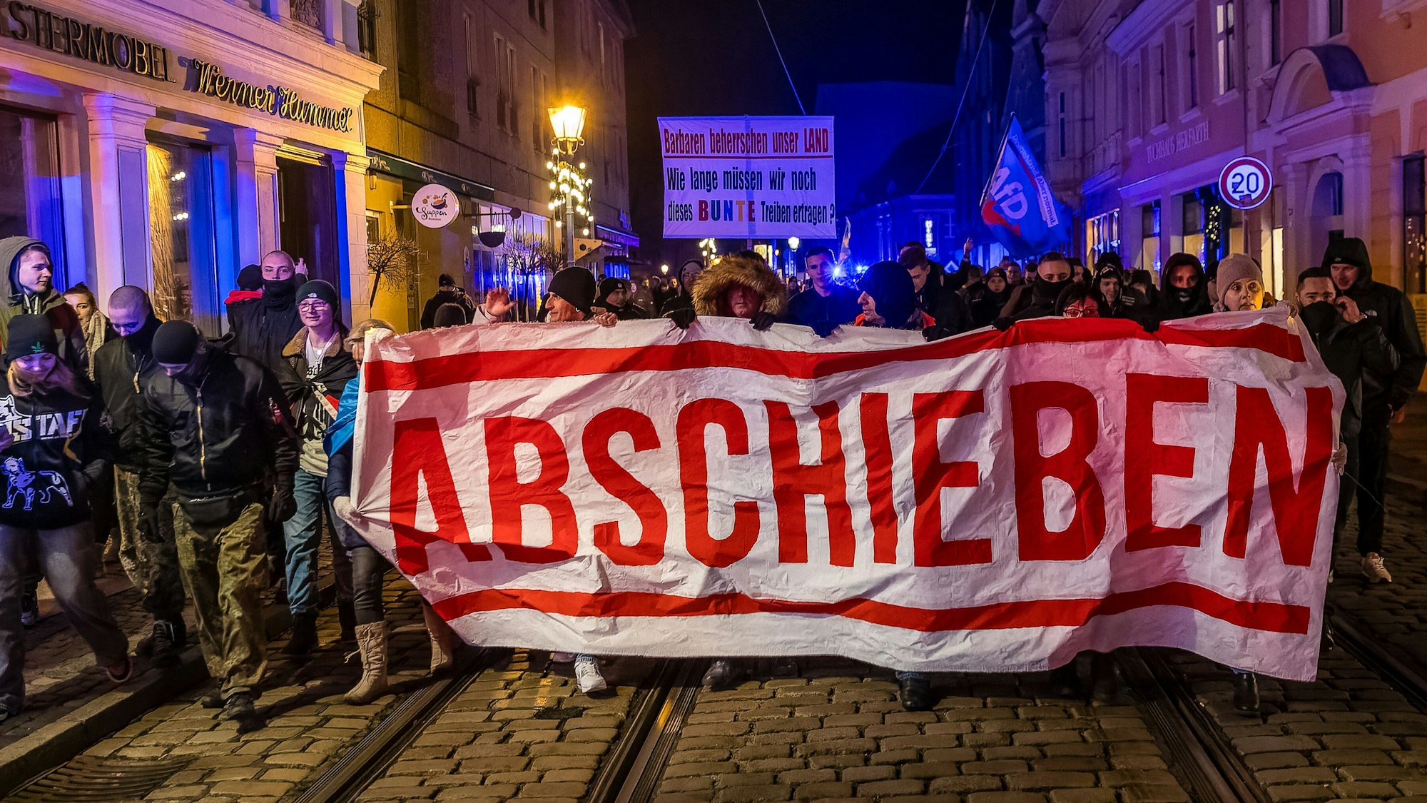 Demonstranten in Cottbus laufen mit einem Plakat «Abschieben» durch die Innenstadt.