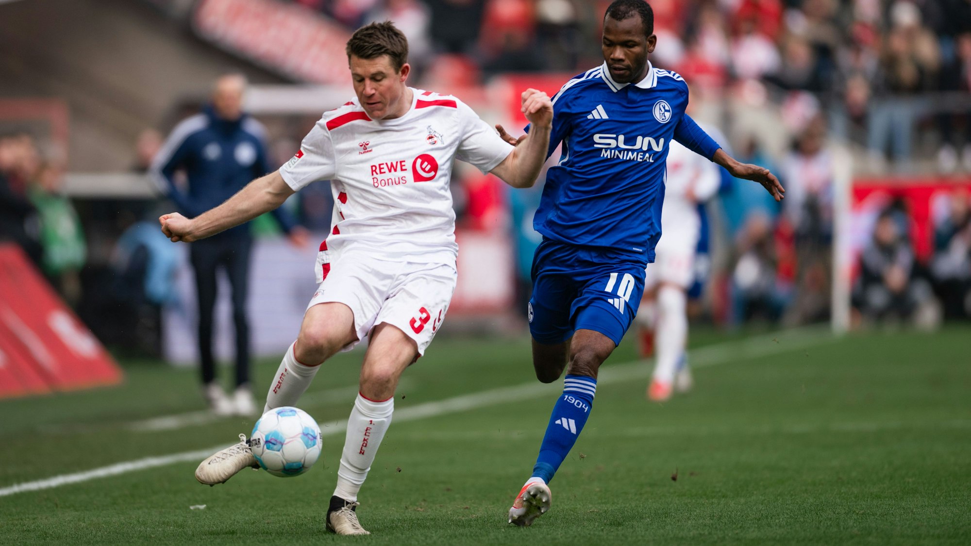 09.02.2025, Nordrhein-Westfalen, Köln: Fußball: 2. Bundesliga, 1. FC Köln - FC Schalke 04, 21. Spieltag, RheinEnergieStadion. Kölns Dominique Heintz (l) und Schalkes Pape Meissa Ba kämpfen um den Ball.