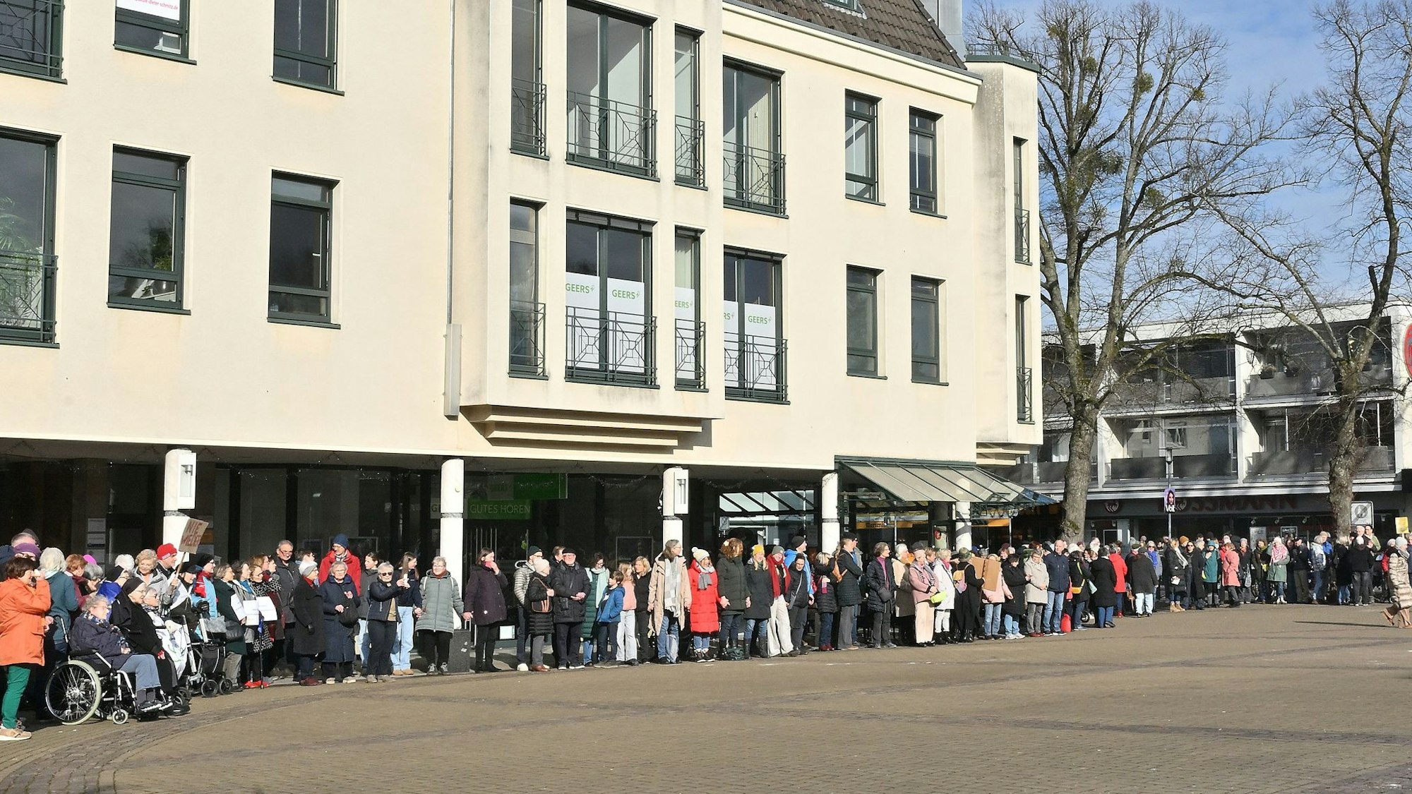 Eine Reihe von Menschen steht vor einem Haus und setzt damit ein Zeichen gegen Rassismus und für Demokratie.