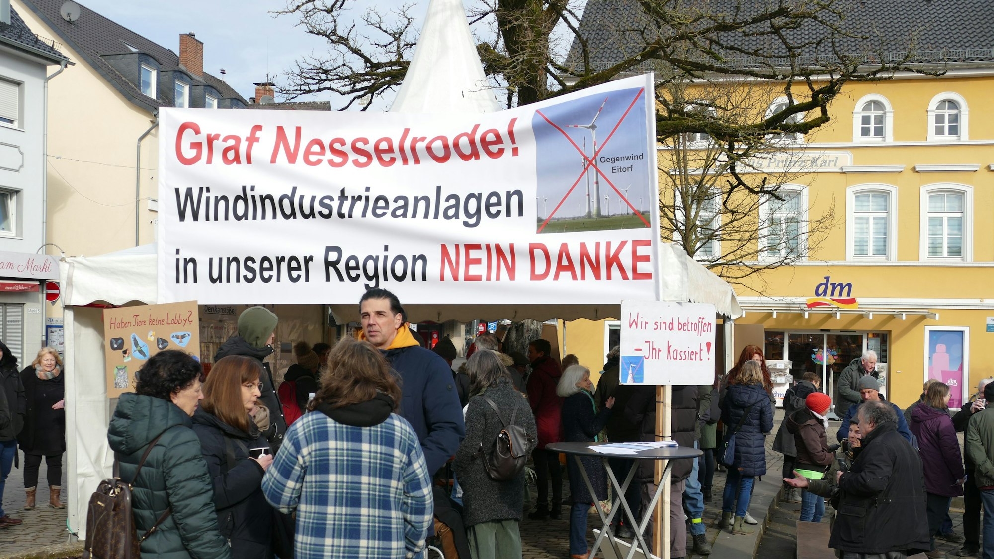 Gegner der rund um Eitorf geplanten Windkraftanlagen stehen mit Transparenten auf dem Eitorfer Marktplatz.