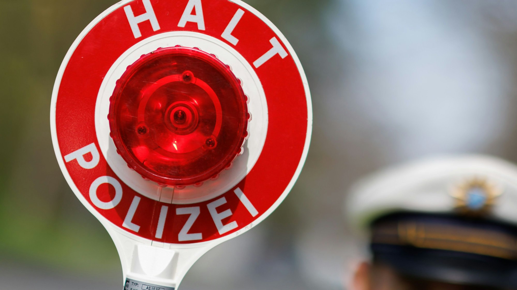 Das Bild zeigt einen Polizeibeamten mit der Kelle "Halt Polizei".