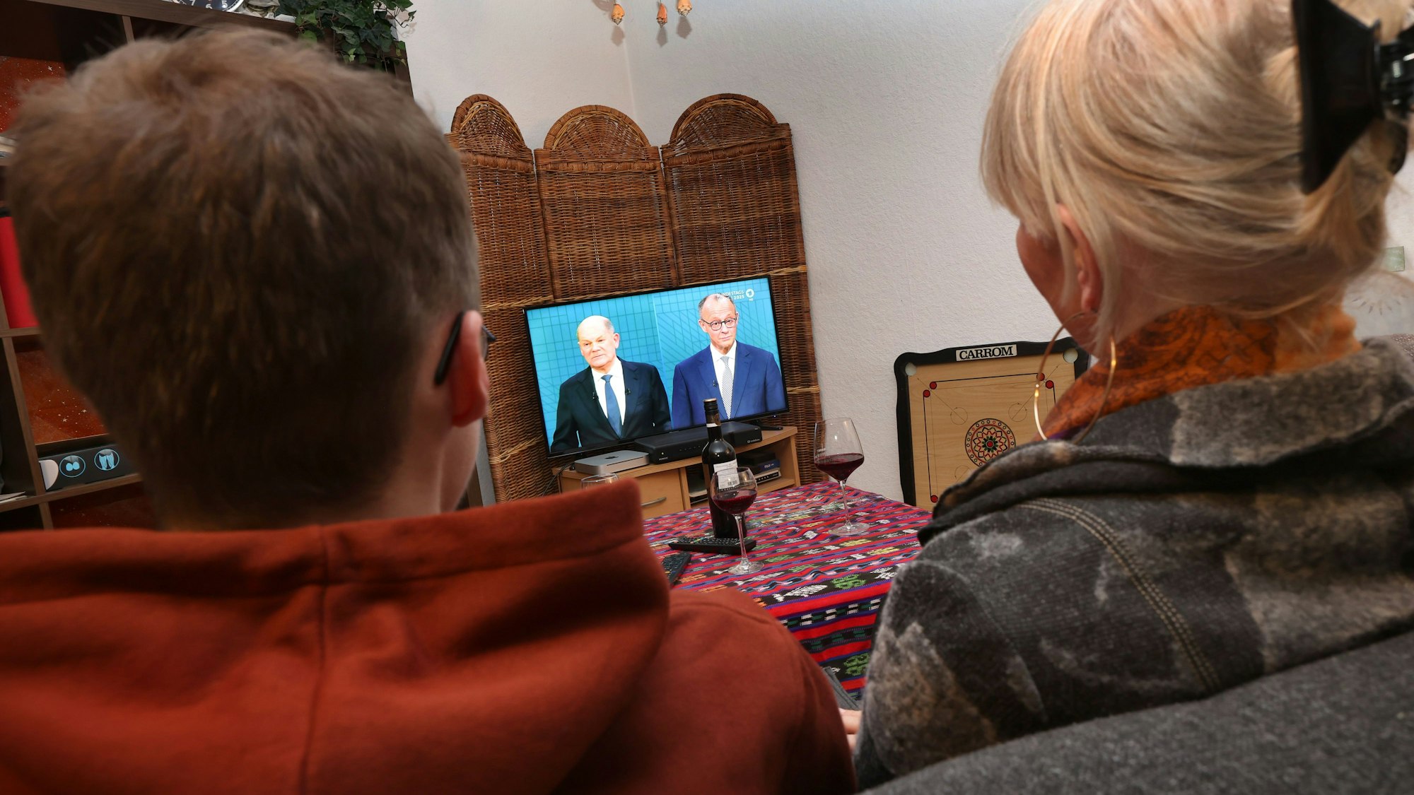 09.02.2025, Bayern, Kaufbeuren: Bewohner einer Wohngemeinschaft sitzen in einem Wohnzimmer vor einem Fernseher, auf dem das TV-Duell zwischen Bundeskanzler Olaf Scholz (SPD) und Friedrich Merz (CDU) übertragen wird. Foto: Karl-Josef Hildenbrand/dpa +++ dpa-Bildfunk +++