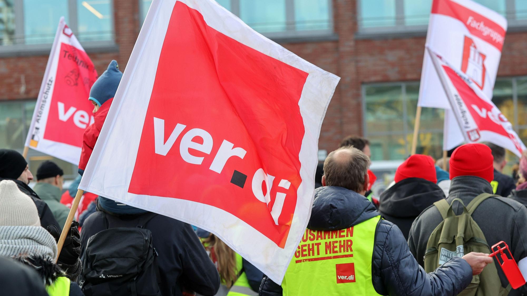 Mit Verdi-Fahnen demonstrieren Teilnehmer während eines Warnstreiks.