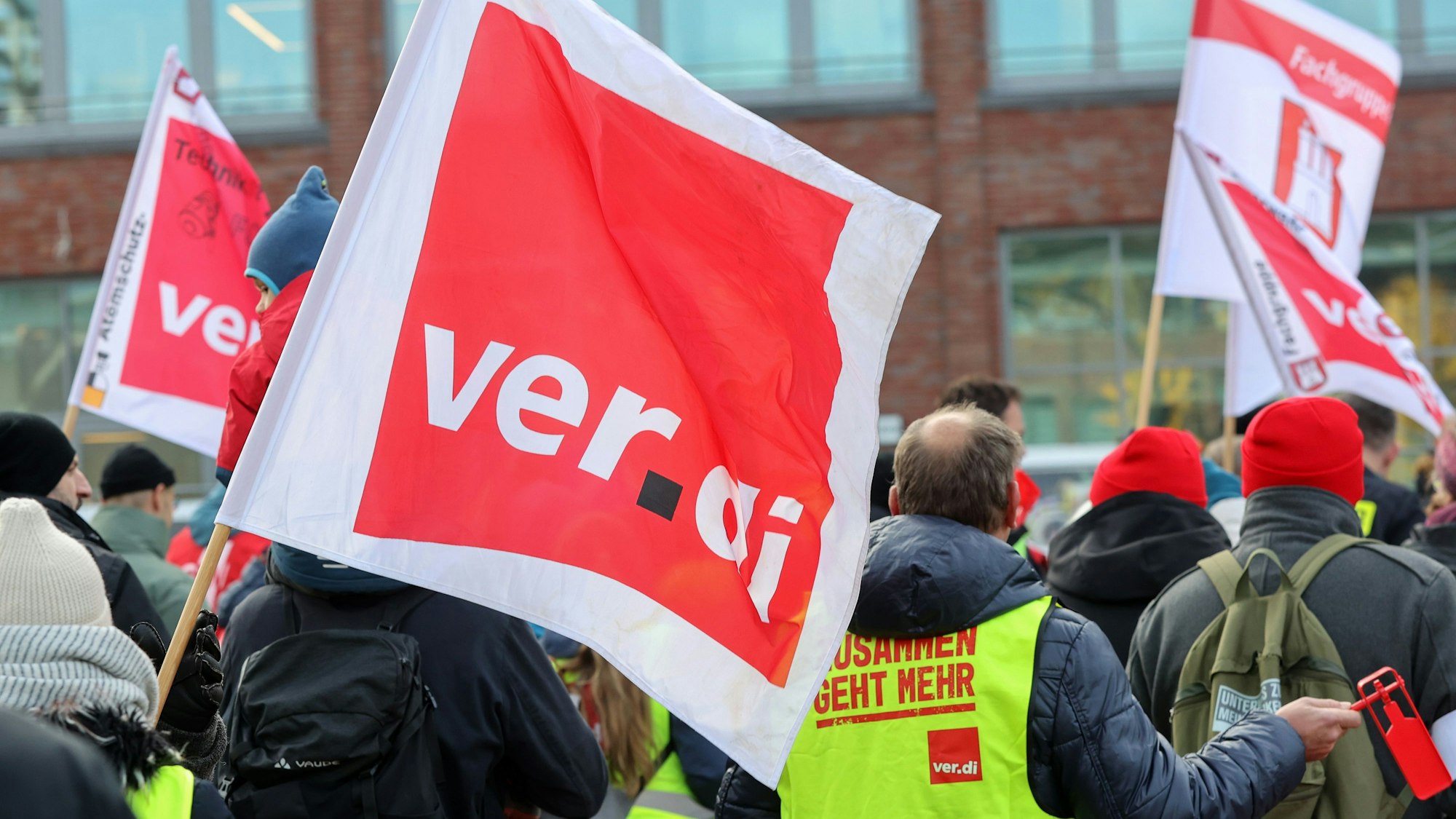 Mit Verdi-Fahnen demonstrieren Teilnehmer während eines Warnstreiks.