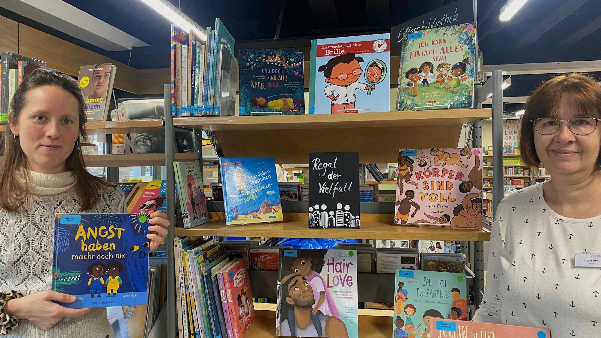 Veronika Heiligmann von der Antidiskriminierungsstelle (links) und Ingrid Pohl von der Stadtbücherei (rechts) vor dem Regal der Vielfalt