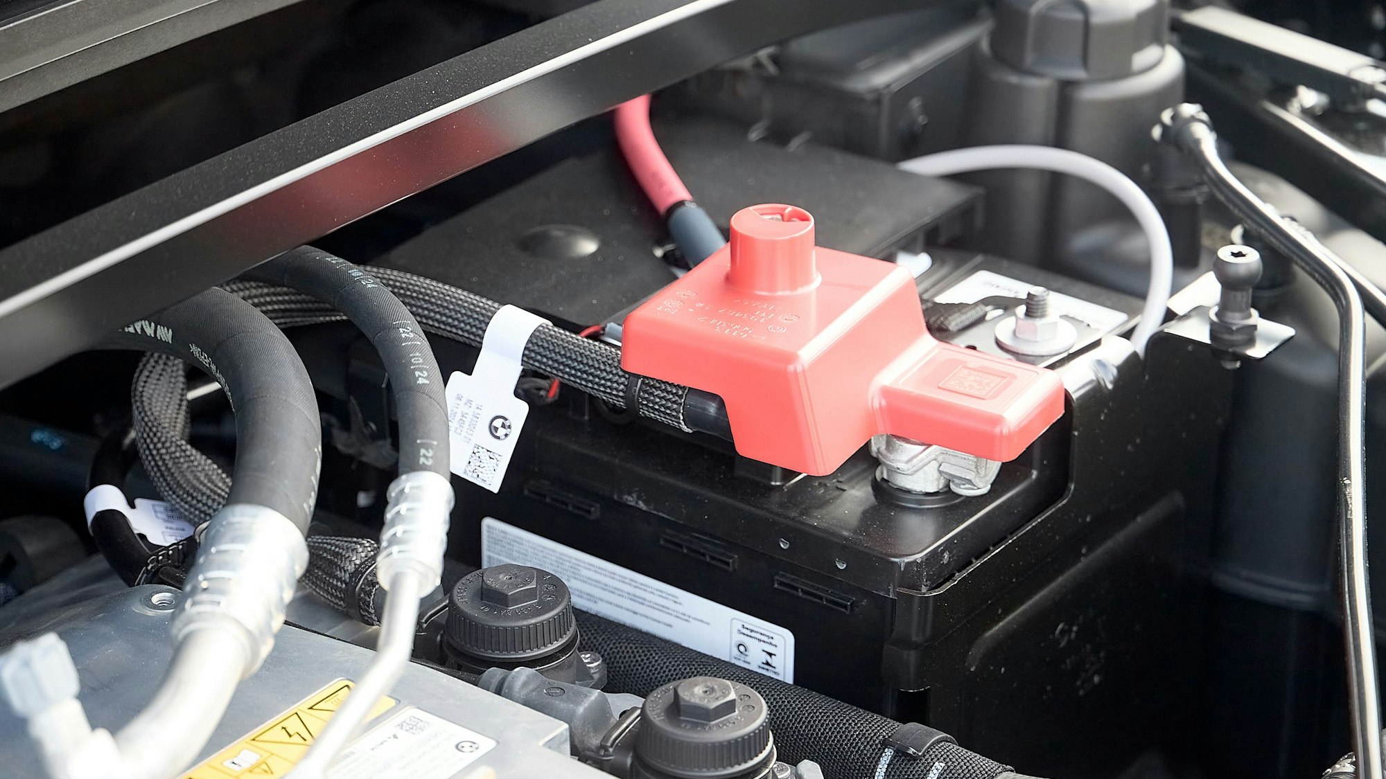 Unter einer roten Kunststoff-Abdeckung ist im Motorraum eines Elektrofahrzeugs von BMW eine kleine Sprengladung angebracht, die bei einem Aufprall die Batterie vom Strom trennt.