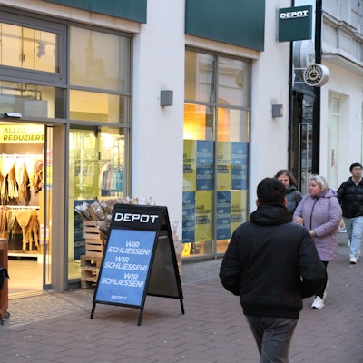 Ein Plakat und Passanten vor einem Geschäft.