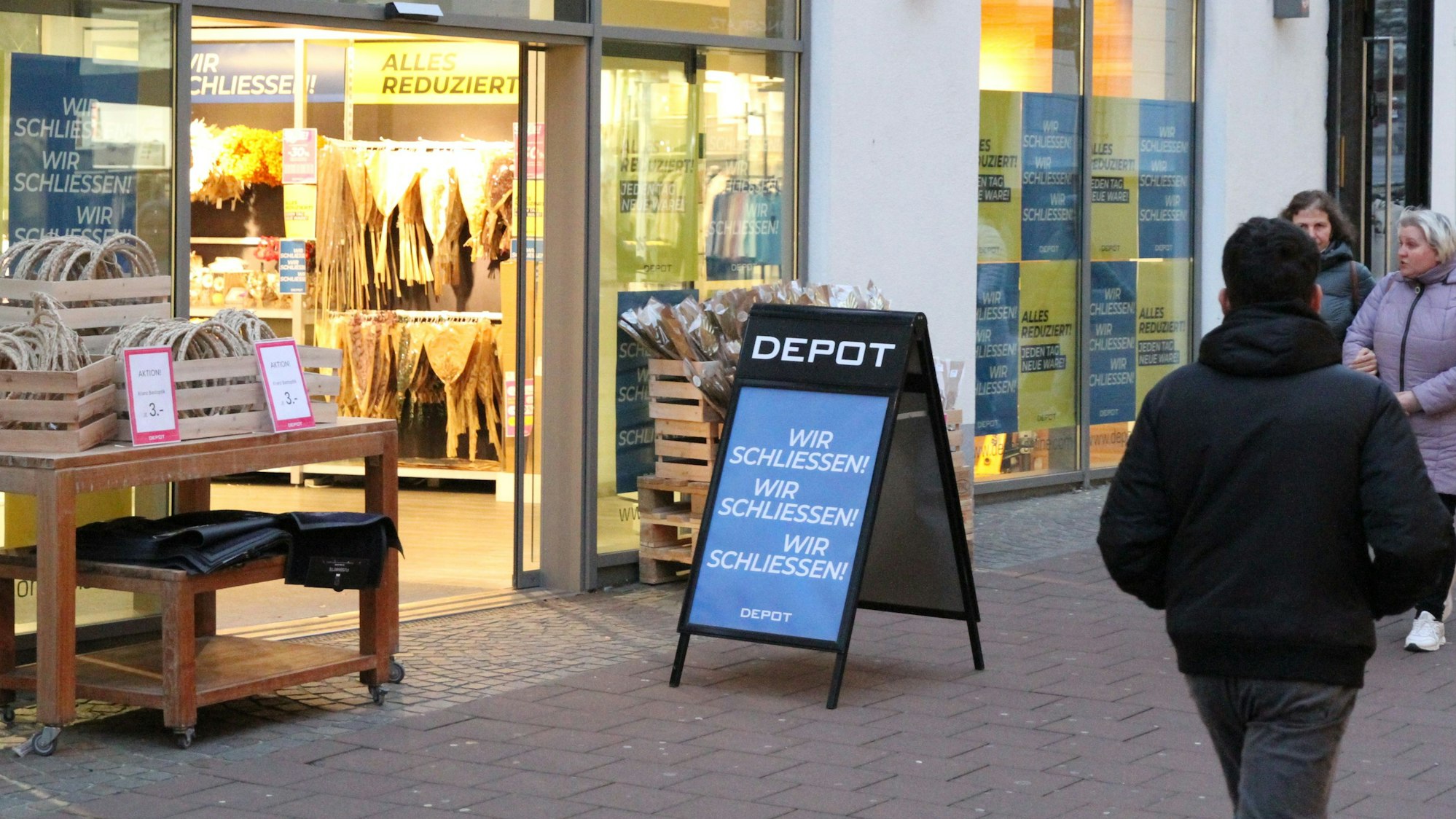 Ein Plakat und Passanten vor einem Geschäft.