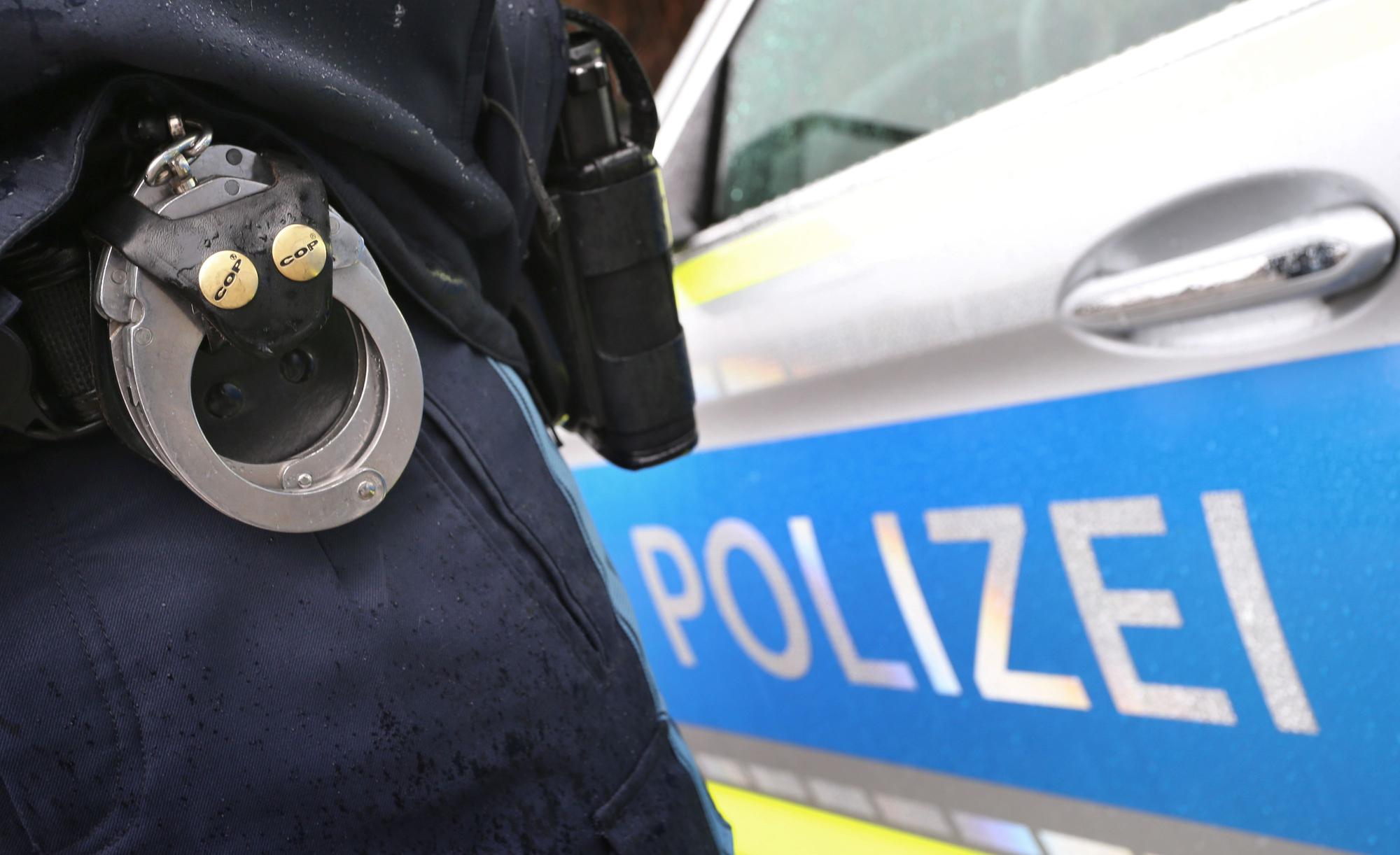 ARCHIV - 15.03.2019, Bayern, Kempten: Ein Polizist mit Handschellen und einer Pistole am Gürtel steht vor einem Streifenwagen. (zu dpa: «Pfarrer überfallen – Verdächtiger in Tram festgenommen») Foto: Karl-Josef Hildenbrand/dpa +++ dpa-Bildfunk +++