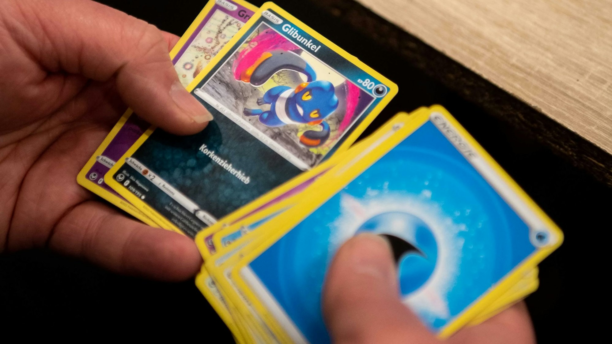 Eine Person hält Pokemon-Karten in ihrer Hand.