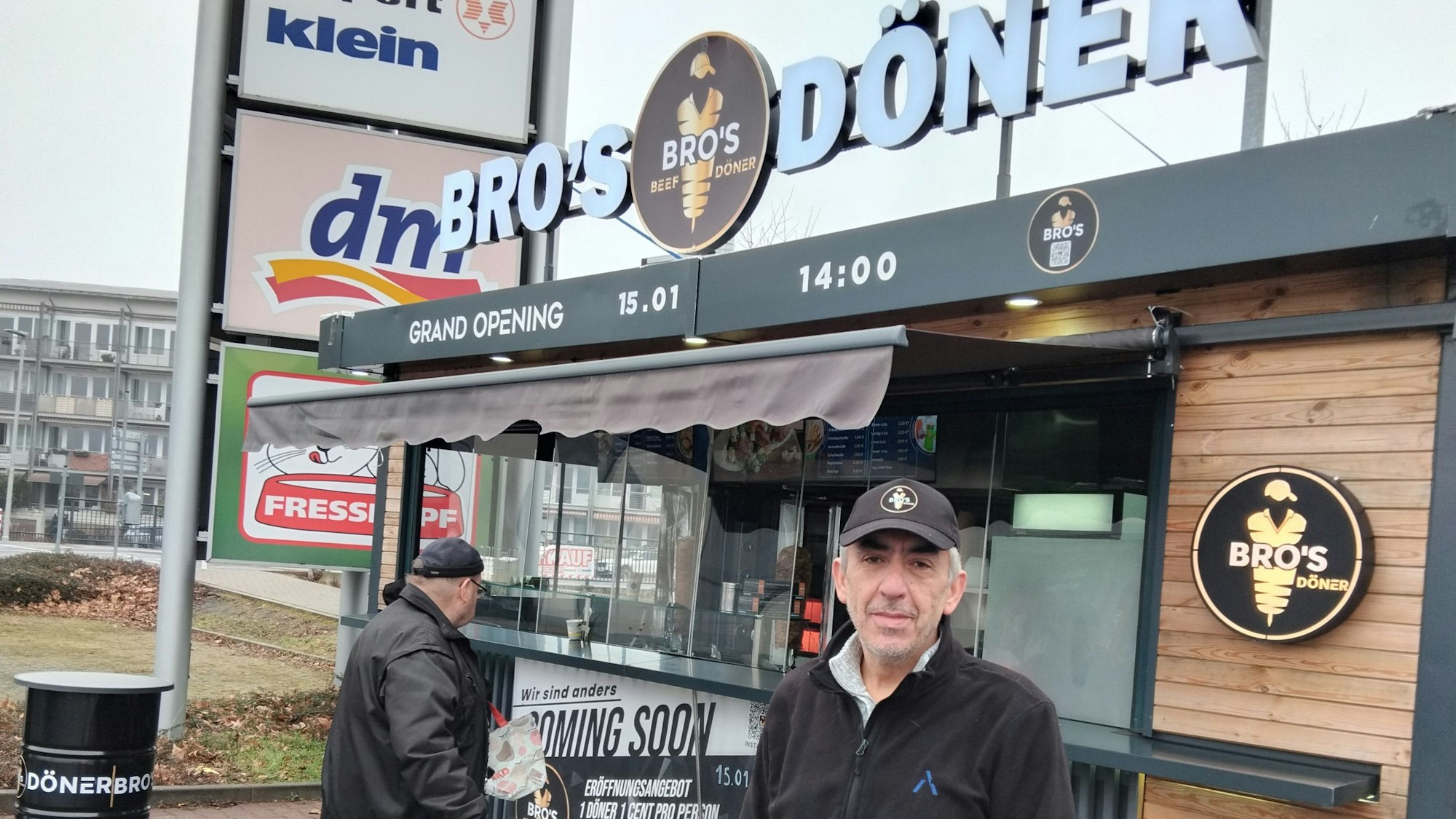 Ein Mann steht vor einem Imbiss-Container