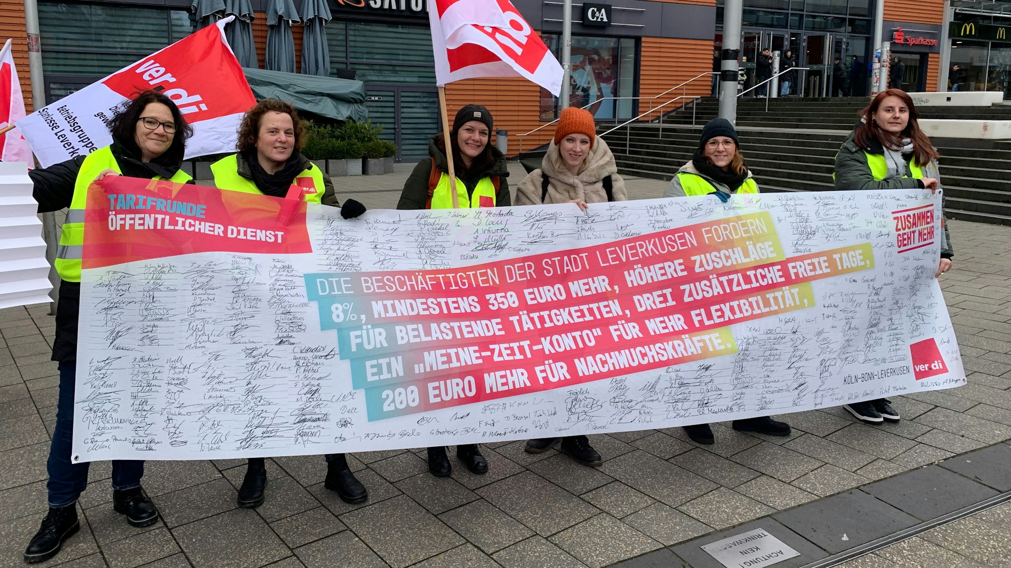 Streikende Menschen halten Banner und Plakate in den Händen.