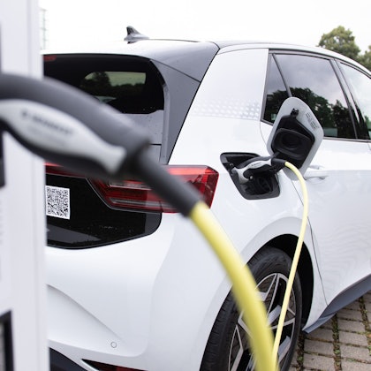 Ein weißes E-Auto an einer Ladestation.