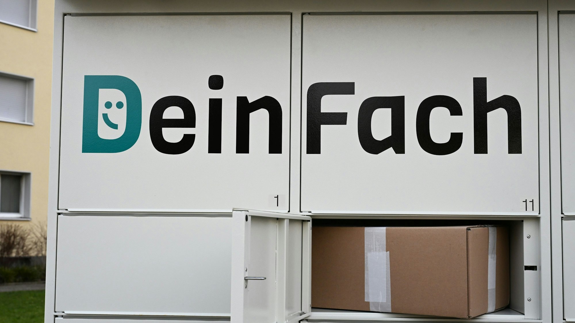 Das Logo der DHL-Tochter DeinFach steht auf einem Paketautomaten der Firma, in einer geöffneten Box liegt ein Paket (gestellte Szene).