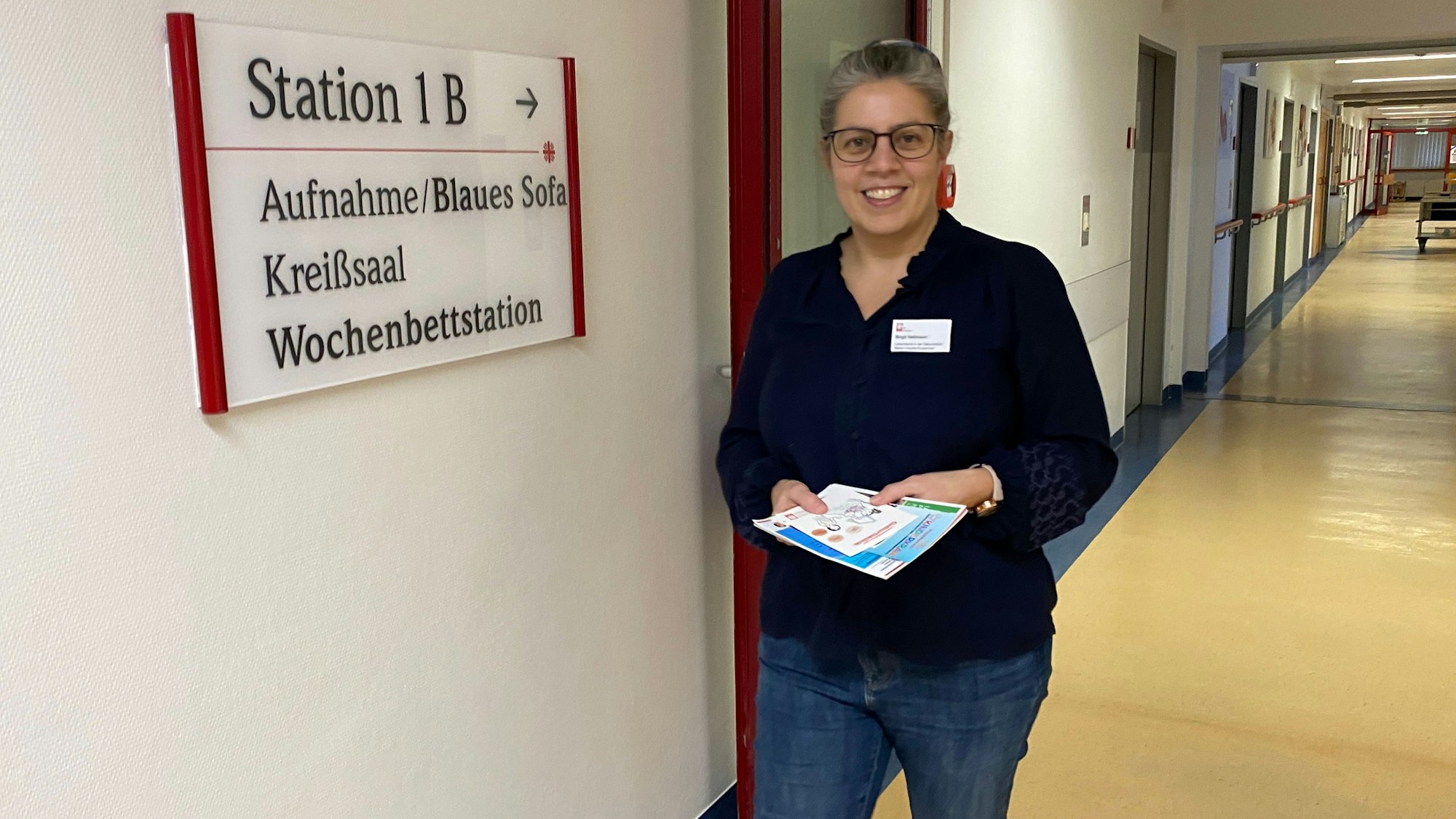Lotsin Birgit Hellmann läuft den Flur der Wochenbettstation im Marien-Hospital Euskirchen entlang. In den Händen hält sie Infomaterial.