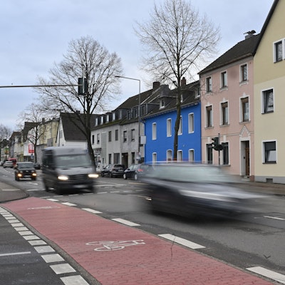 Auf der Straße sind außer Pkw, ein Fahrrad sowie ein Laster unterwegs.