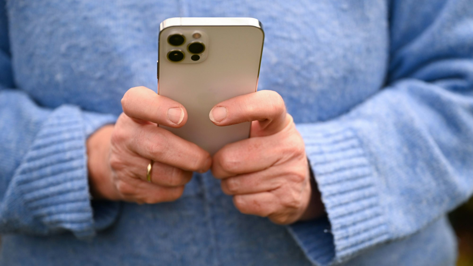 Ein Mensch hält ein Smartphone in der Hand.