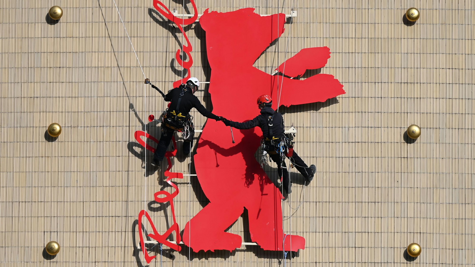 Fassadenkletterer montieren einen der Berlinale-Bären an der Fassade des Kinos Zoo-Palast.