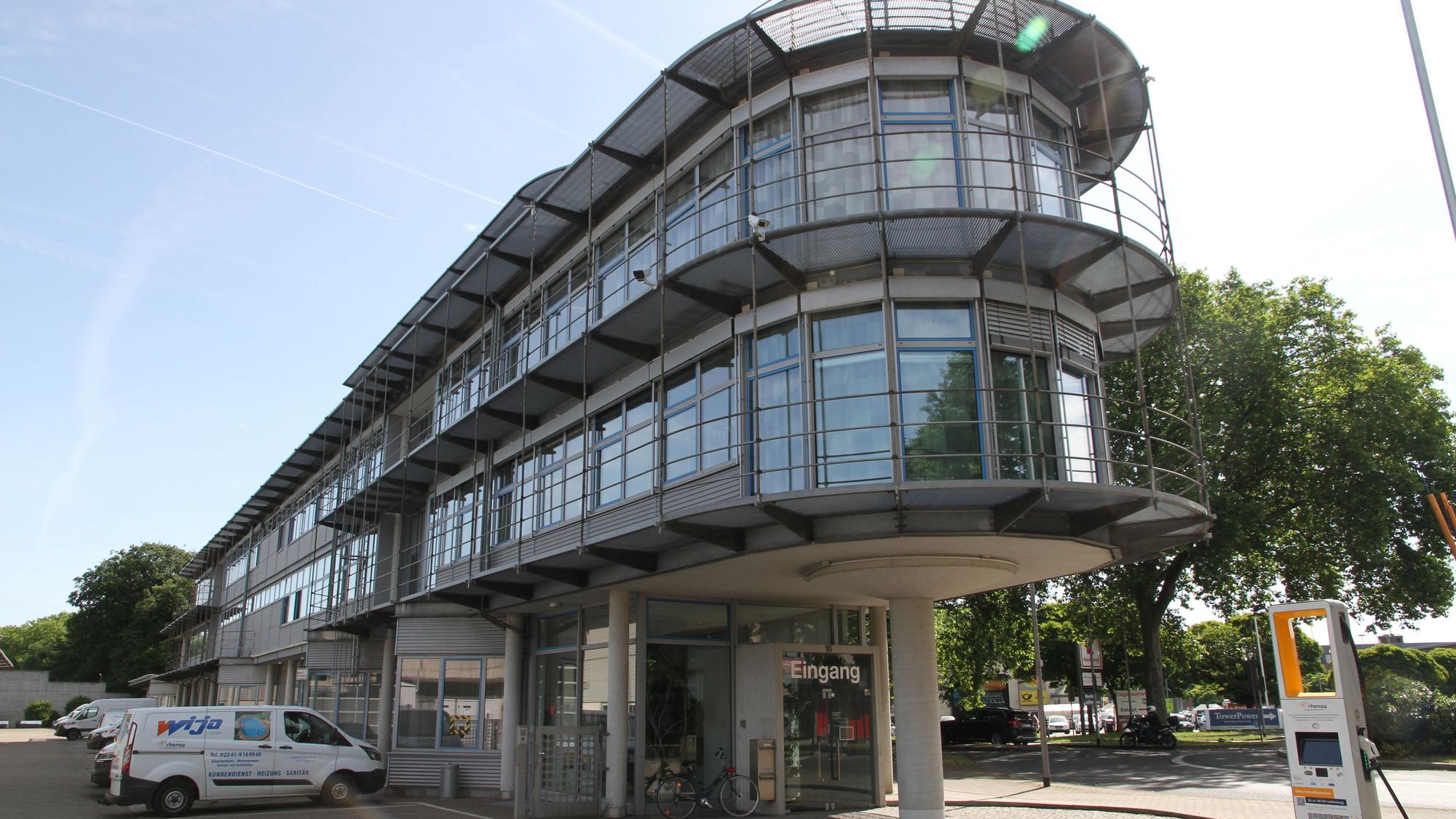 Ein schmales verglastes Verwaltungsgebäude mit drei Etagen und abgerundeter Gebäudefront.