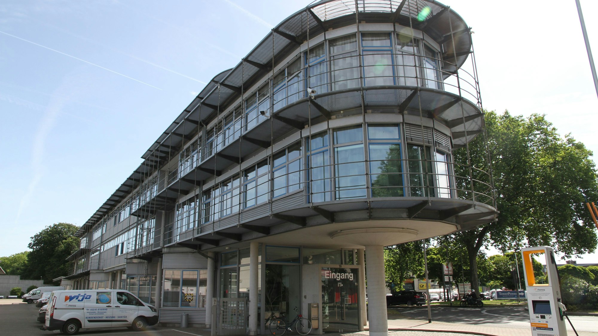 Ein schmales verglastes Verwaltungsgebäude mit drei Etagen und abgerundeter Gebäudefront.