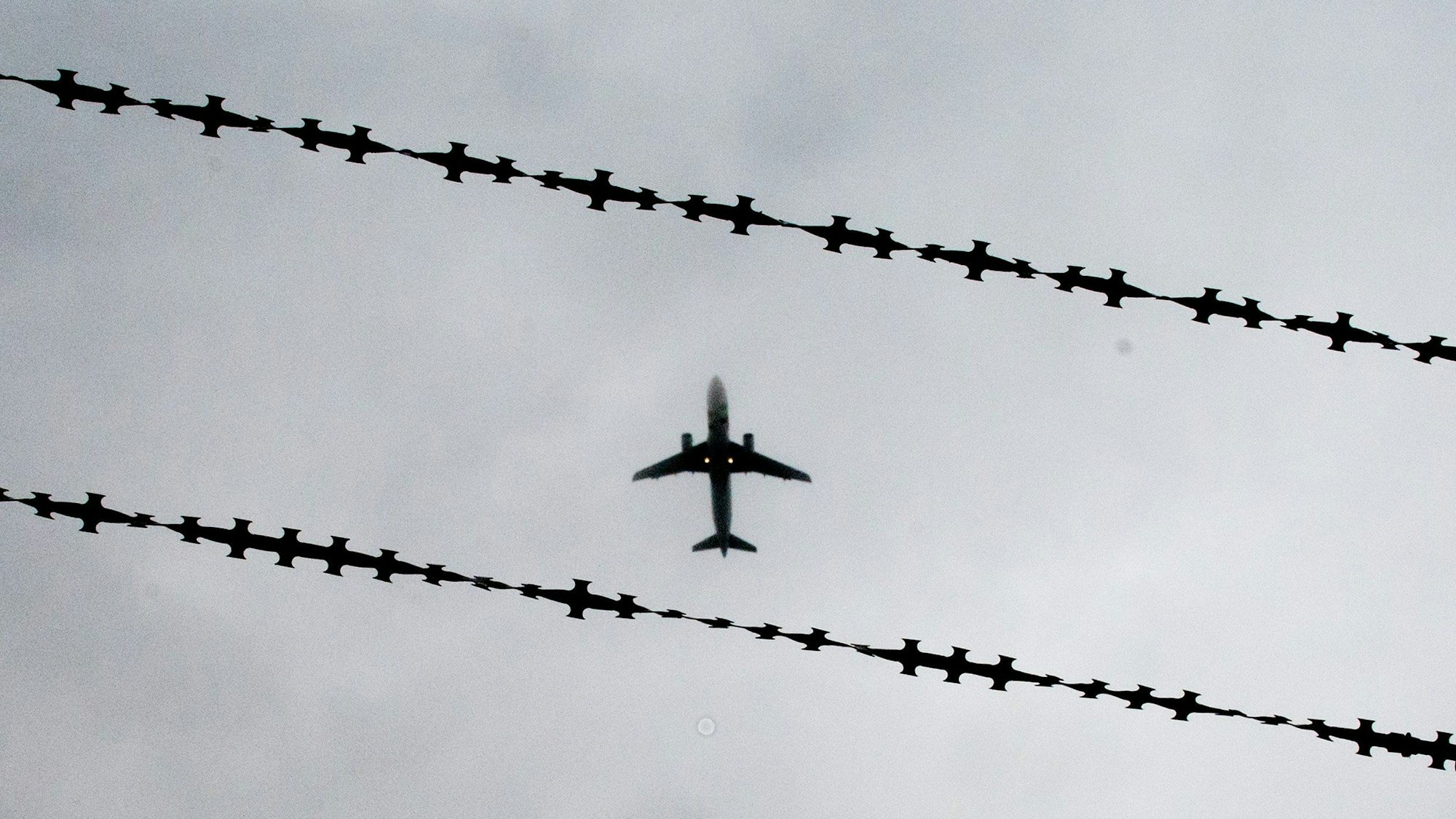 Ein Flugzeug ist hinter Stacheldraht zu sehen.