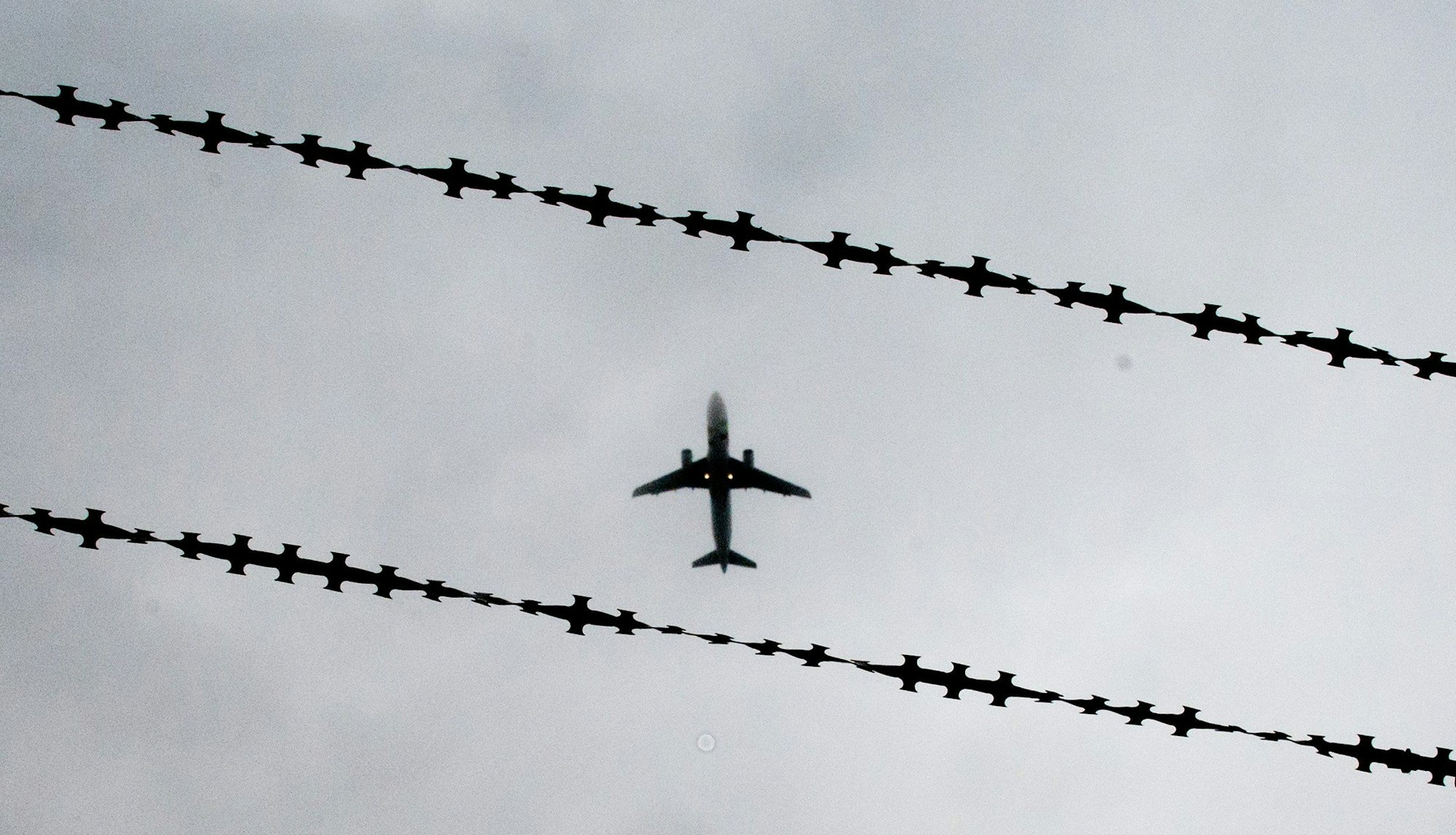 ARCHIV - 22.10.2015, Niedersachsen, Hannover: Ein Flugzeug ist hinter Stacheldraht zu sehen. Nordrhein-Westfalen hat im vergangenen Jahr 3118 Menschen abgeschoben - im Vergleich der Bundesländer sind das die meisten. (zu dpa: «Land NRW führt erstmals eigenen Abschiebeflug durch») Foto: Julian Stratenschulte/dpa +++ dpa-Bildfunk +++