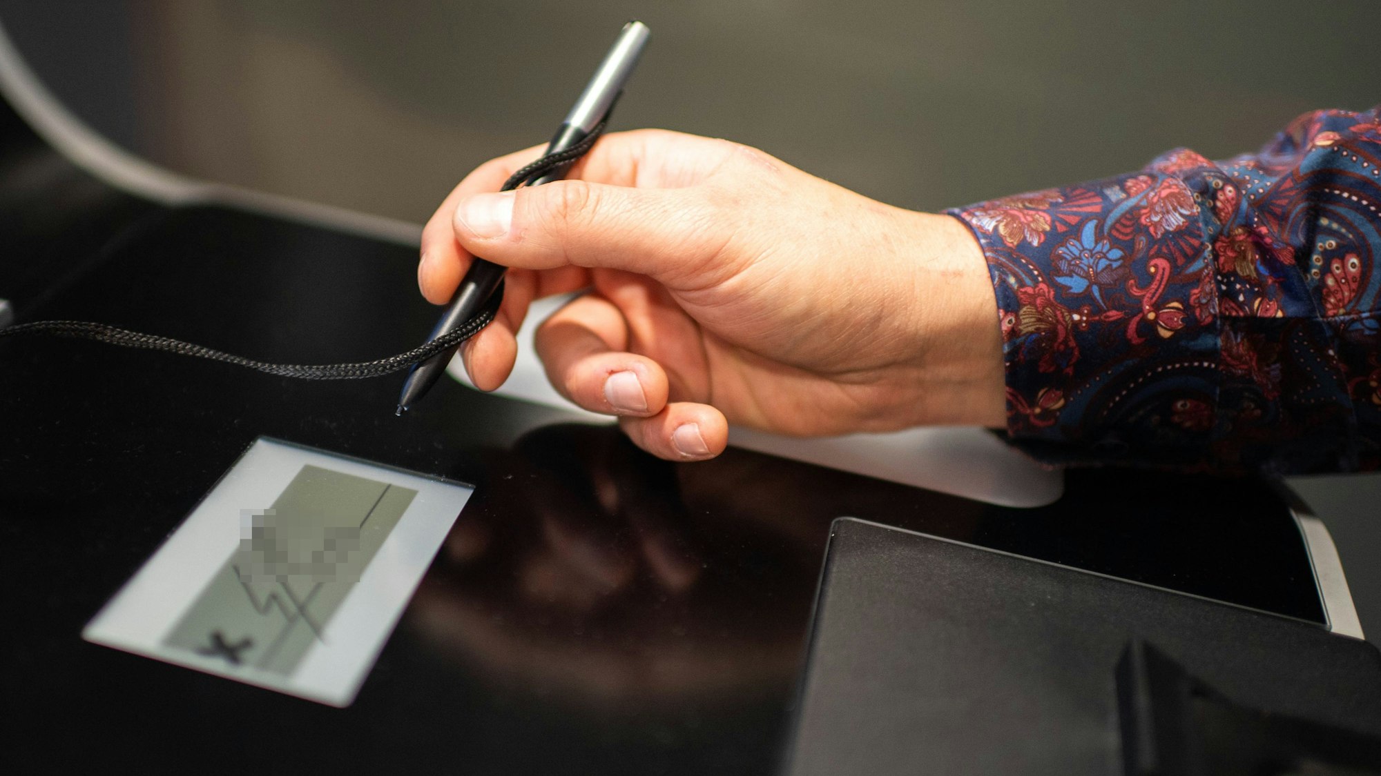 Das Bild zeigt einen Mann, der in ein entsprechendes Feld seine Unterschrift setzt.