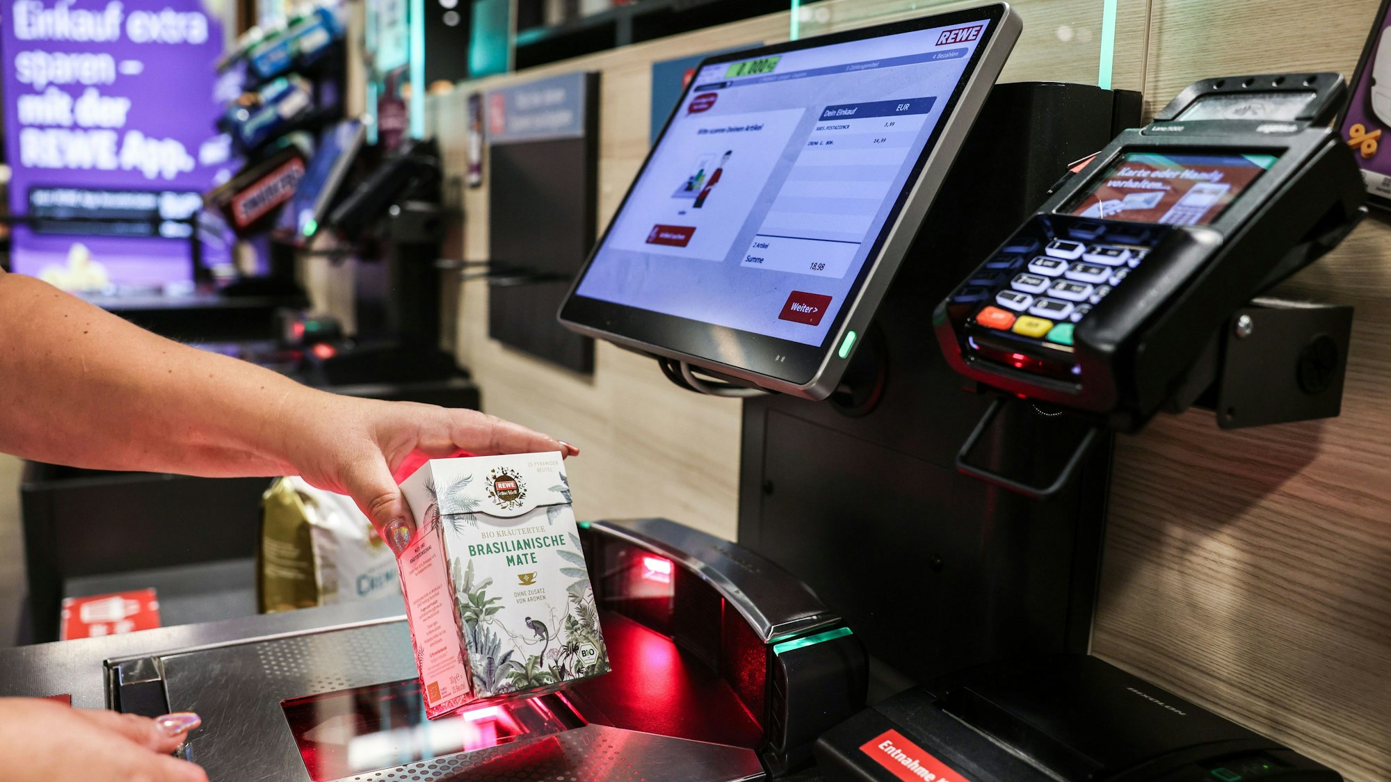 Eine Frau scannt ein Produkt an einer Selbstbedienungskasse.