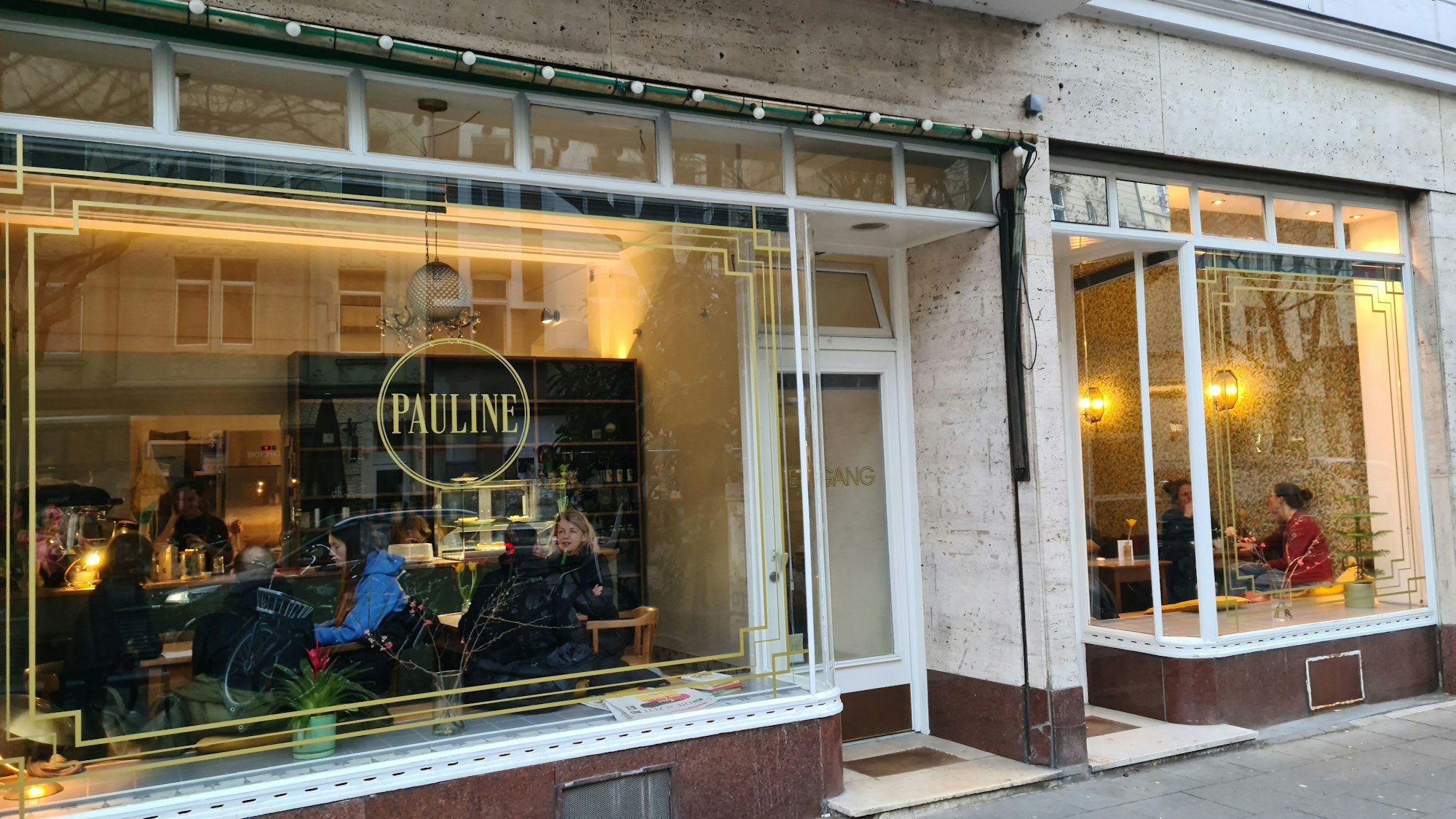 Blick auf eine Fensterfront eines Cafés; in Goldbuchstaben und oval umrandet steht der Schriftzug Pauline auf einem Fenster.