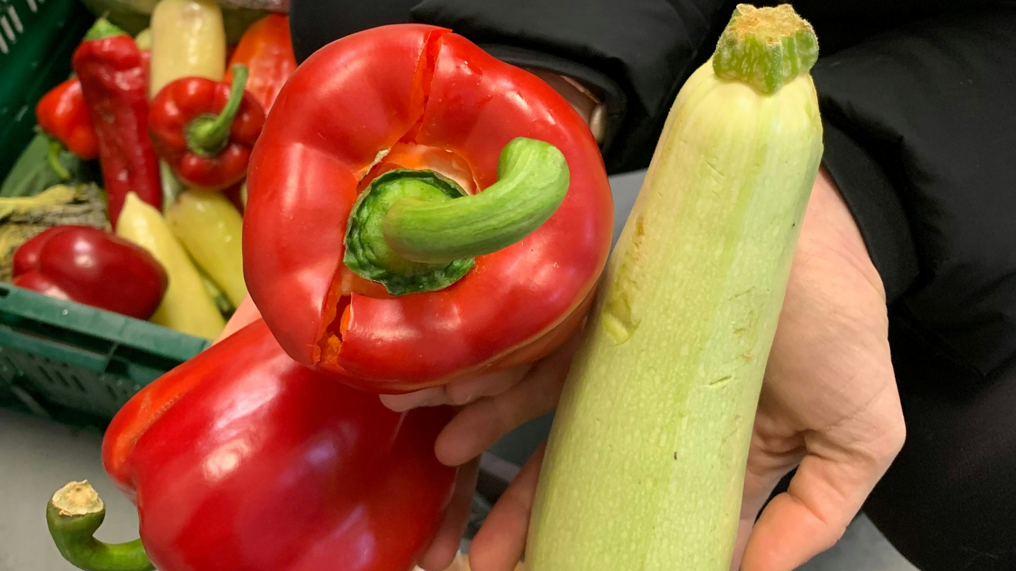 Der Stiel einer roten Paprika ist eingedrückt. Eine grüne Zucchini weist leichte Druckstellen auf.